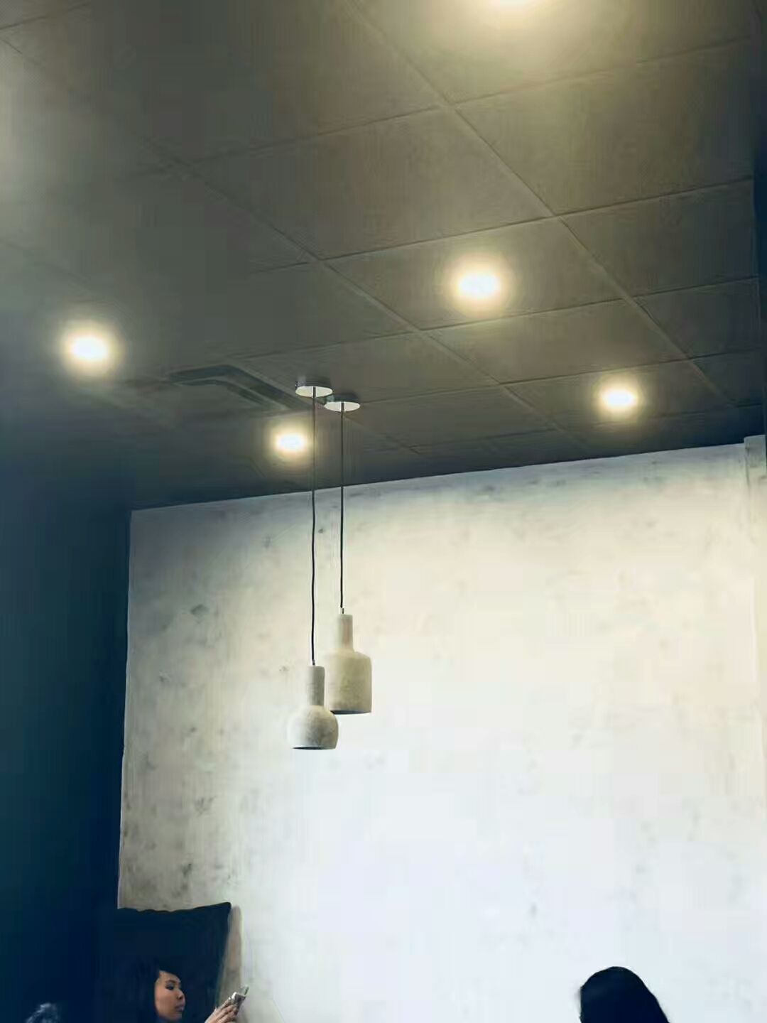This image highlights the interior lighting design of a renovated bubble tea shop in Scarborough. The space features modern pendant lights combined with recessed ceiling lighting, creating a warm and inviting atmosphere for customers. The minimalist wall finish and carefully arranged lighting enhance the overall commercial interior design while providing comfortable illumination for the seating area. This renovation reflects a clean, modern aesthetic commonly used in contemporary bubble tea shop interiors.