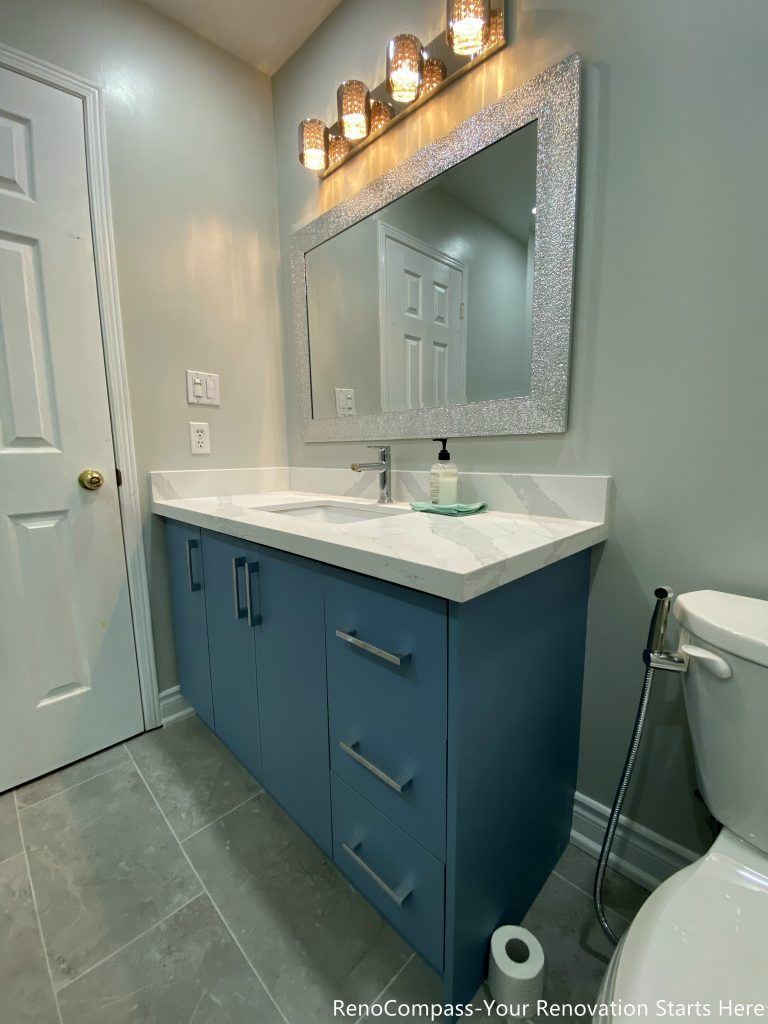 This Mississauga bathroom renovation captures the vanity from an angled view, highlighting the blue cabinetry, integrated drawers, and clean countertop edges. The design focuses on storage efficiency and daily usability, while warm lighting and neutral finishes help balance the overall look of the space.
City: Mississauga · Toronto contractor: Reno Compass