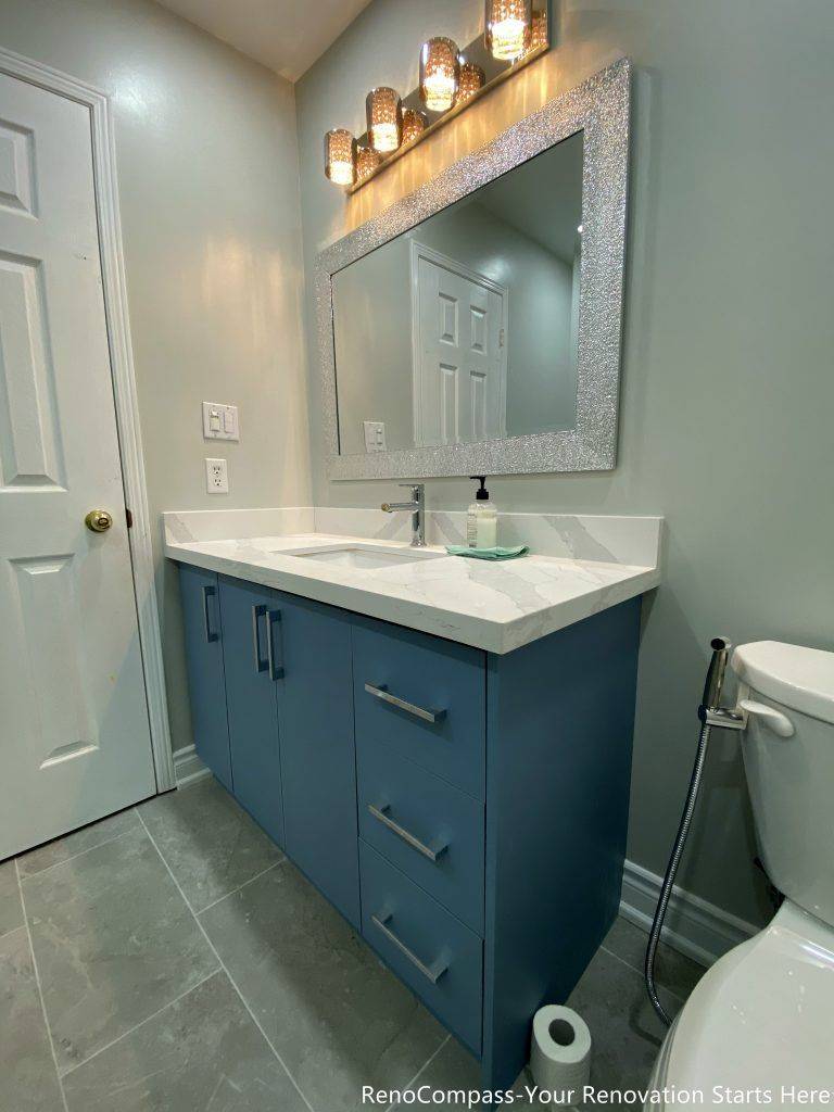 This Mississauga bathroom renovation captures the vanity from an angled view, highlighting the blue cabinetry, integrated drawers, and clean countertop edges. The design focuses on storage efficiency and daily usability, while warm lighting and neutral finishes help balance the overall look of the space.
City: Mississauga · Toronto contractor: Reno Compass