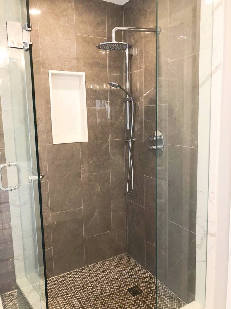 This Richmond Hill bathroom renovation features a modern walk-in glass shower with a sleek rainfall showerhead, built-in wall niche, and textured mosaic shower floor for enhanced safety and style. Large-format wall tiles and a frameless glass enclosure create a clean, open, and contemporary look. The upgraded shower design improves daily functionality while delivering a spa-like experience. Completed by a professional Toronto renovation company, this bathroom upgrade combines durable materials, elegant finishes, and modern comfort for long-term use.