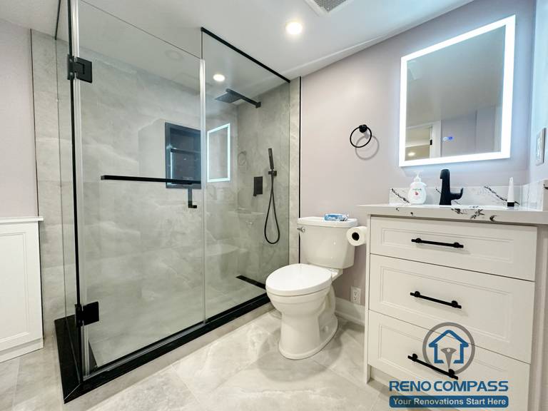 his Mississauga bathroom renovation features a full glass shower enclosure, modern tile finishes, and a custom vanity with integrated storage. The design improves functionality, enhances visual openness, and delivers a clean, contemporary bathroom layout for everyday use.