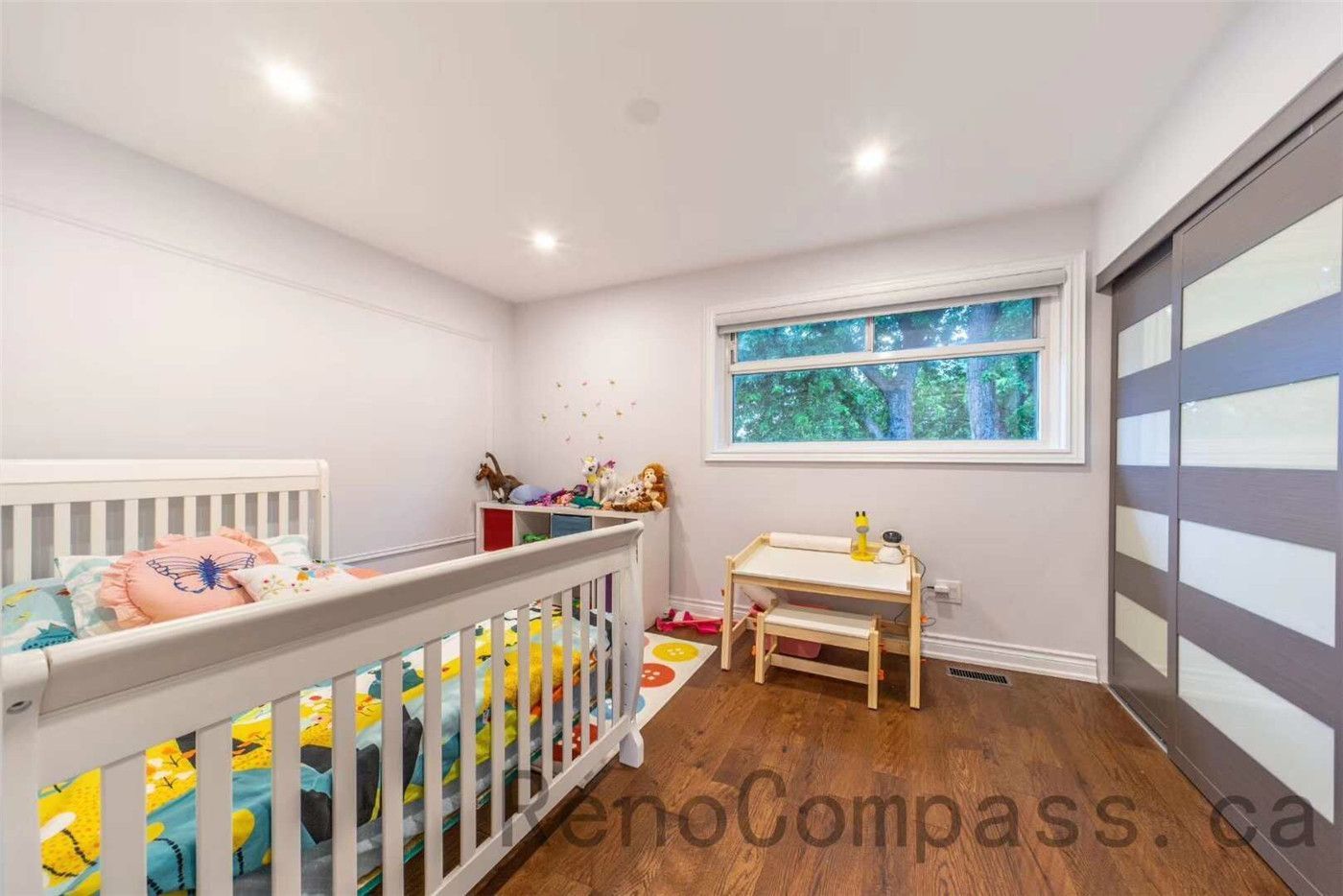 This kids’ bedroom is part of a North York interior renovation project, designed to create a bright, safe, and functional living space. The room features smooth white walls, recessed ceiling lights, warm hardwood flooring, and a wide horizontal window that brings in natural light. Clean lines, practical layout planning, and child-friendly proportions ensure both comfort and long-term usability, reflecting professional interior renovation standards in Toronto homes.