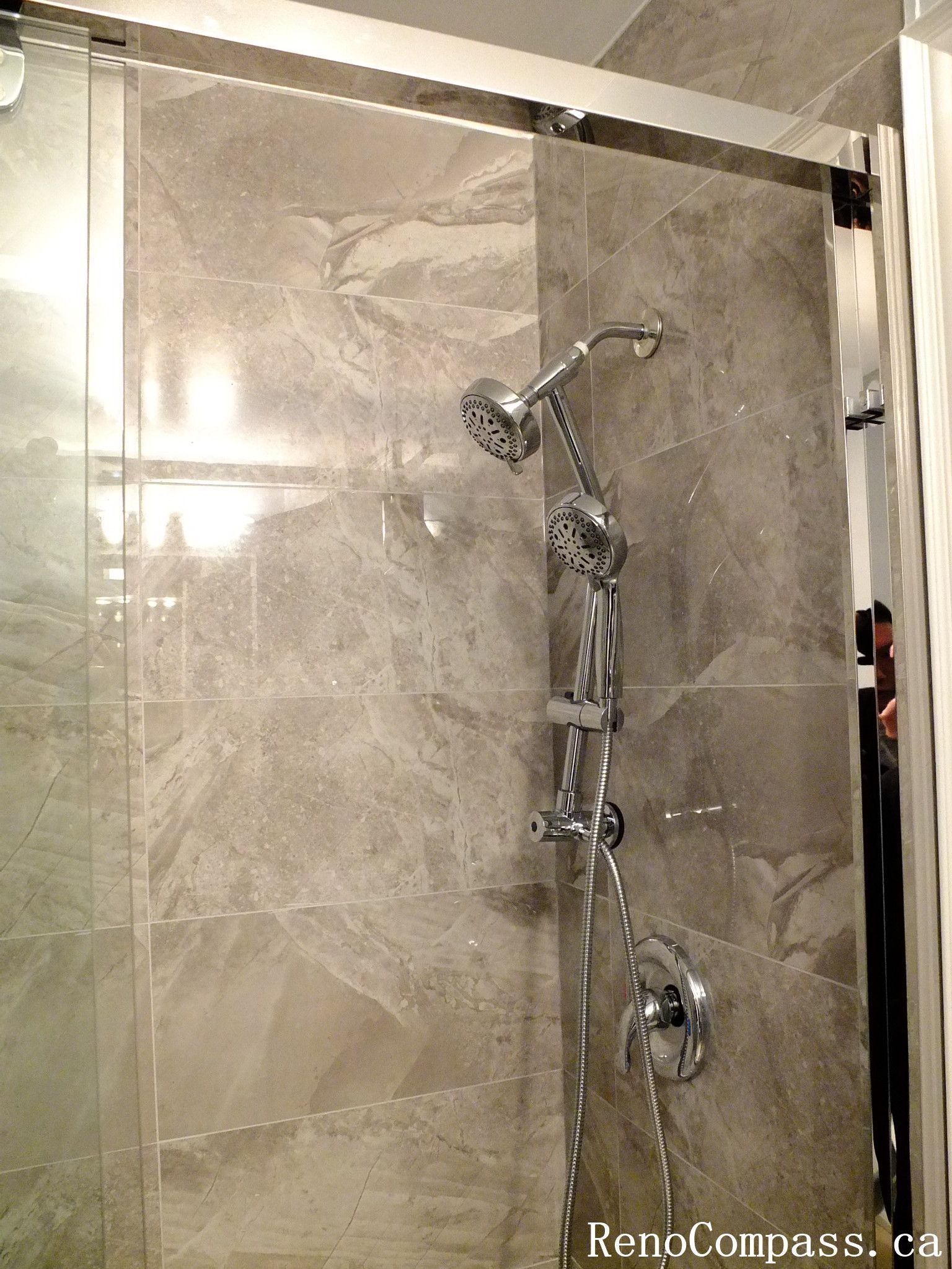Stylish bathroom renovation in Richmond Hill featuring a frameless glass shower enclosure, marble-look tile walls, and a sleek handheld shower system. Elegant, contemporary design crafted by RenoCompass.ca for a luxurious home update.