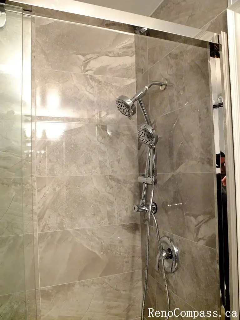 Stylish bathroom renovation in Richmond Hill featuring a frameless glass shower enclosure, marble-look tile walls, and a sleek handheld shower system. Elegant, contemporary design crafted by RenoCompass.ca for a luxurious home update.