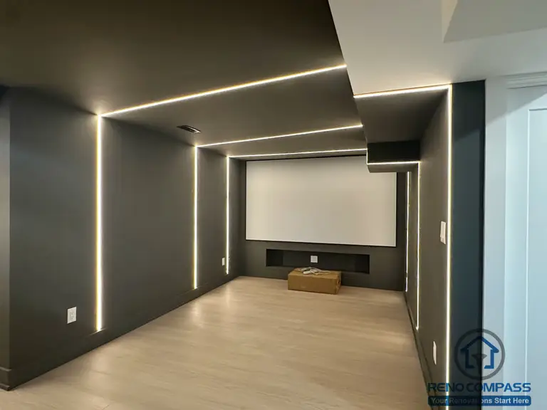 This Markham interior renovation features a custom-designed home theater space focused on immersive viewing and clean architectural lines. Integrated linear LED lighting is built into the walls and ceiling to create a controlled, cinematic atmosphere while enhancing spatial depth. Dark matte finishes reduce visual distraction, allowing the screen to remain the focal point of the room. The layout prioritizes acoustics, lighting balance, and comfort, resulting in a dedicated media room that feels modern, minimal, and purpose-built.
