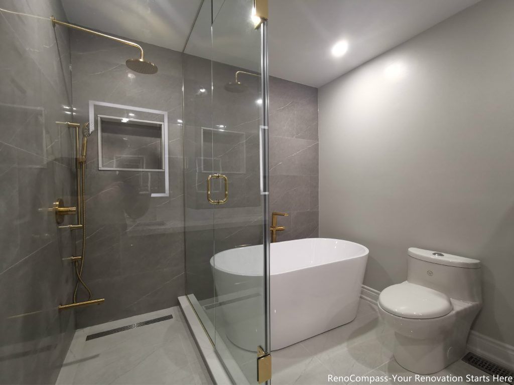 This Oakville master bathroom full renovation features a modern walk-in glass shower, freestanding bathtub, and sleek contemporary layout designed for comfort and luxury. Large-format marble-style tiles, premium gold fixtures, recessed shower niche, and linear drain create a clean, spa-inspired atmosphere. The combination of frameless glass enclosure, modern toilet installation, and bright lighting enhances both functionality and visual space. Completed by a trusted Toronto renovation company, this bathroom upgrade delivers long-lasting quality, elegant design, and increased property value for the homeowner.