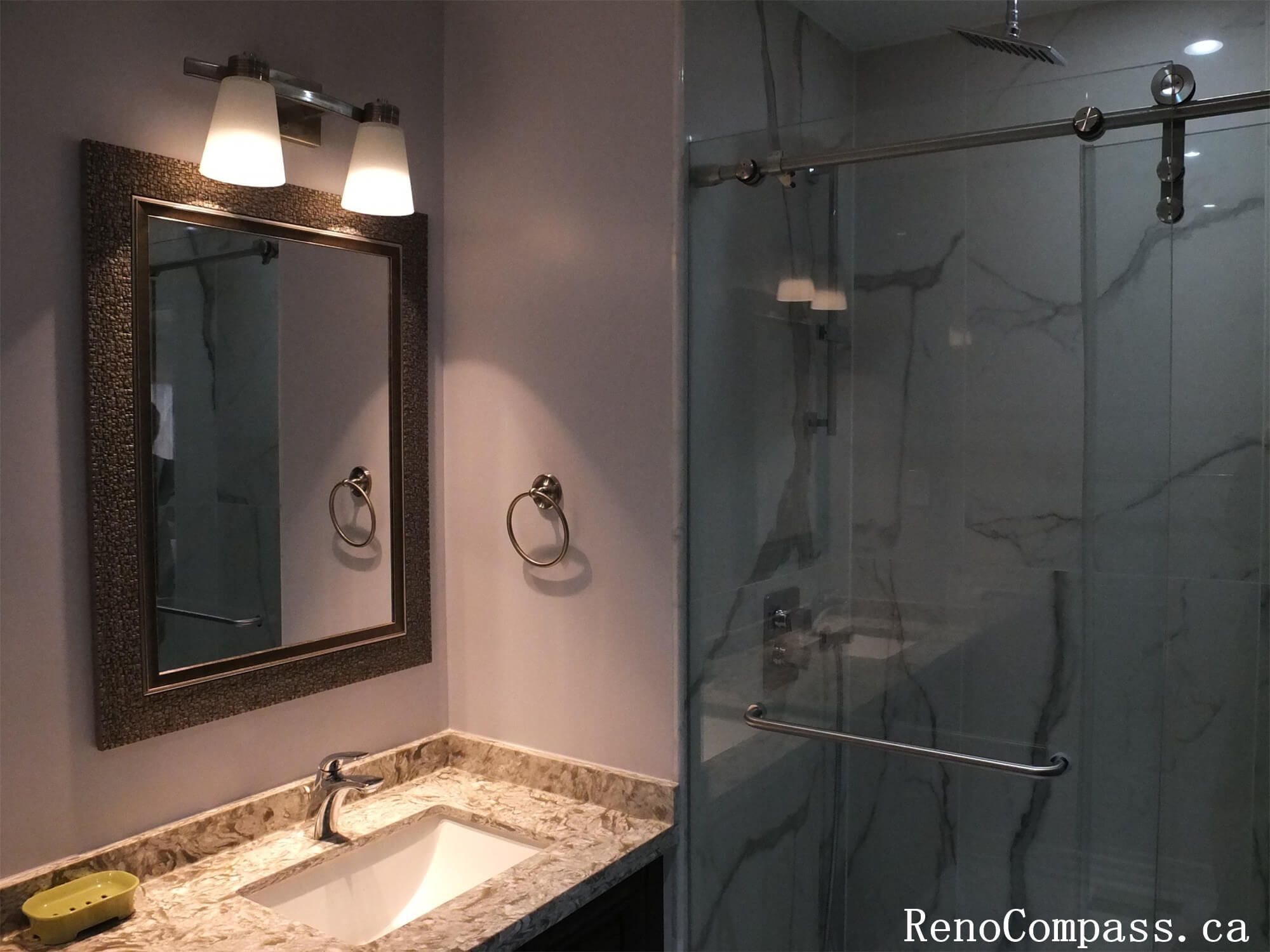 This Richmond Hill interior renovation features a stylish bathroom vanity upgrade with a marble-style quartz countertop, modern undermount sink, and custom cabinetry for improved storage. Elegant wall-mounted lighting and framed mirrors enhance brightness and functionality, creating a clean and contemporary bathroom space. The updated fixtures and finishes provide both durability and timeless appeal for everyday use. Completed by a reliable Toronto renovation company, this bathroom renovation adds comfort, practicality, and long-term value to the home.