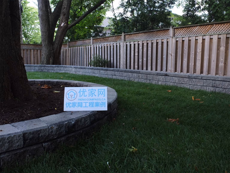 This North York landscaping renovation features a custom tree planter retaining wall integrated into a spacious backyard lawn. The circular stone retaining wall protects mature trees while defining planting areas and maintaining clean lawn edges. Proper grading and base preparation ensure long-term stability, drainage efficiency, and durability. Combined with a continuous linear retaining wall along the fence line, the design creates a cohesive, low-maintenance backyard landscape that balances natural elements with functional hardscape solutions for residential properties in North York.