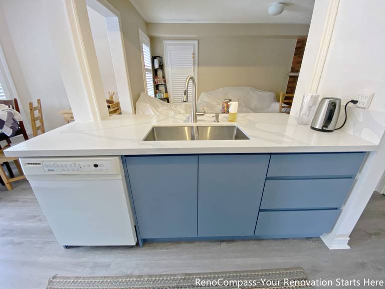 This image features a functional kitchen island completed as part of a Mississauga kitchen renovation. The island is topped with a durable quartz countertop and includes an undermount sink, modern faucet, and an integrated dishwasher for efficient cleanup. Base cabinetry provides concealed storage while maintaining a clean and streamlined appearance. Positioned to connect the kitchen with the surrounding living space, this island design supports everyday meal preparation, cleaning, and casual use in modern Mississauga homes.