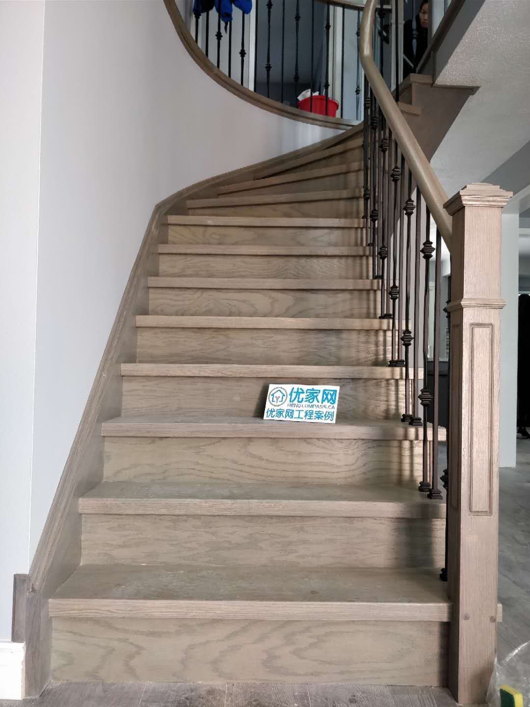 Elegant staircase renovation in Ajax featuring natural wood stair treads, curved staircase design, and modern black iron balusters. The upgrade enhances both safety and visual appeal, creating a warm and contemporary transition between floors in this residential interior renovation project completed by a professional Toronto renovation company.