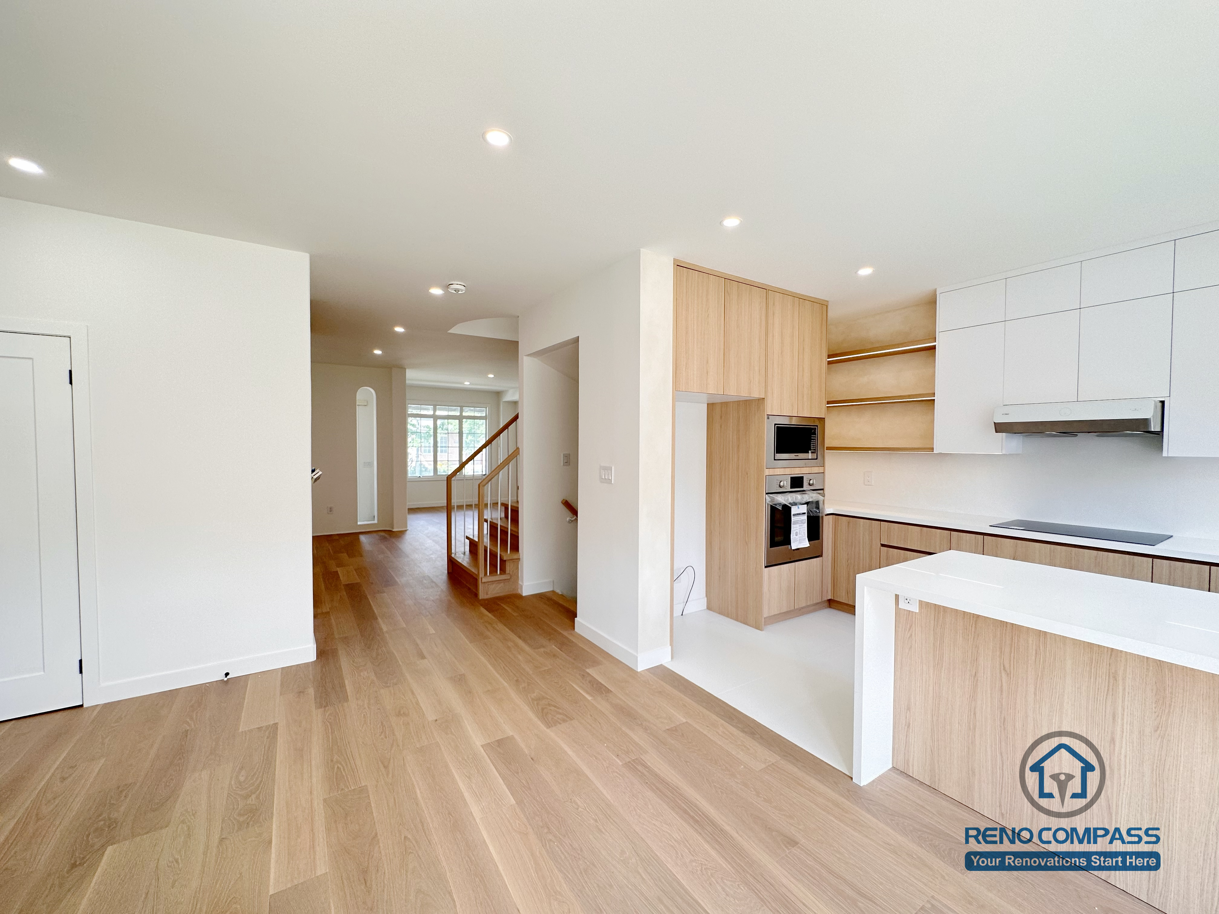 Open main floor renovation in Markham highlighting the connection between the kitchen and surrounding living spaces. The design features custom cabinetry, built-in appliances, recessed ceiling lights, and wide-plank wood flooring to create a bright, cohesive, and functional home layout.