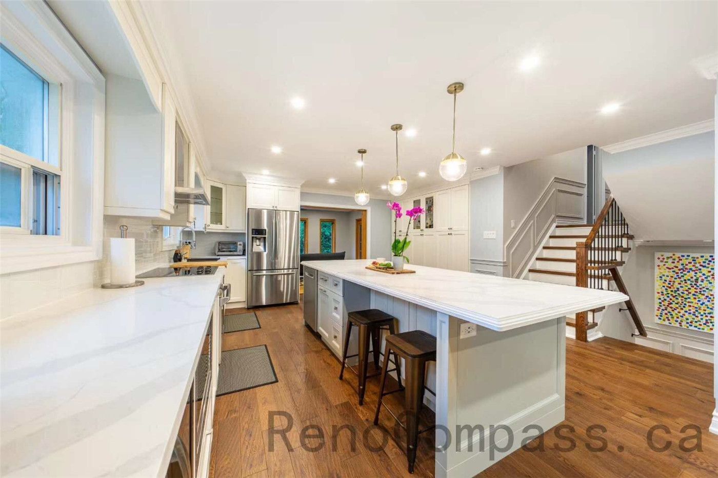 This North York interior renovation showcases a bright open-concept kitchen designed with a spacious quartz island, custom white cabinetry, and modern pendant lighting. The layout connects seamlessly with the surrounding living space and staircase area, creating a functional and elegant environment for cooking and entertaining. Completed by a professional Toronto renovation company, the project features high-quality finishes, warm hardwood flooring, and a clean contemporary design that enhances both comfort and home value.