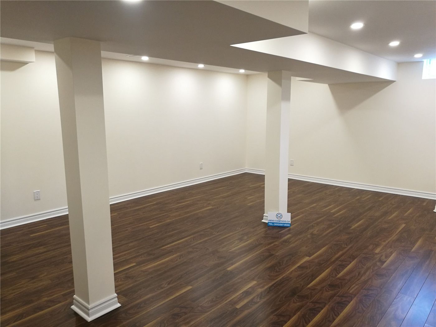 This Aurora basement renovation project features newly installed dark hardwood flooring, a clean drywall ceiling with integrated pot lights, and a bright, open layout that maximizes usable living space. Structural beams and support columns are neatly finished to maintain a modern and uncluttered appearance. The renovated basement is ideal for a family room, home gym, or multi-purpose living area. Completed by a professional Toronto renovation company, this project enhances both comfort and property value for the homeowner in Aurora.