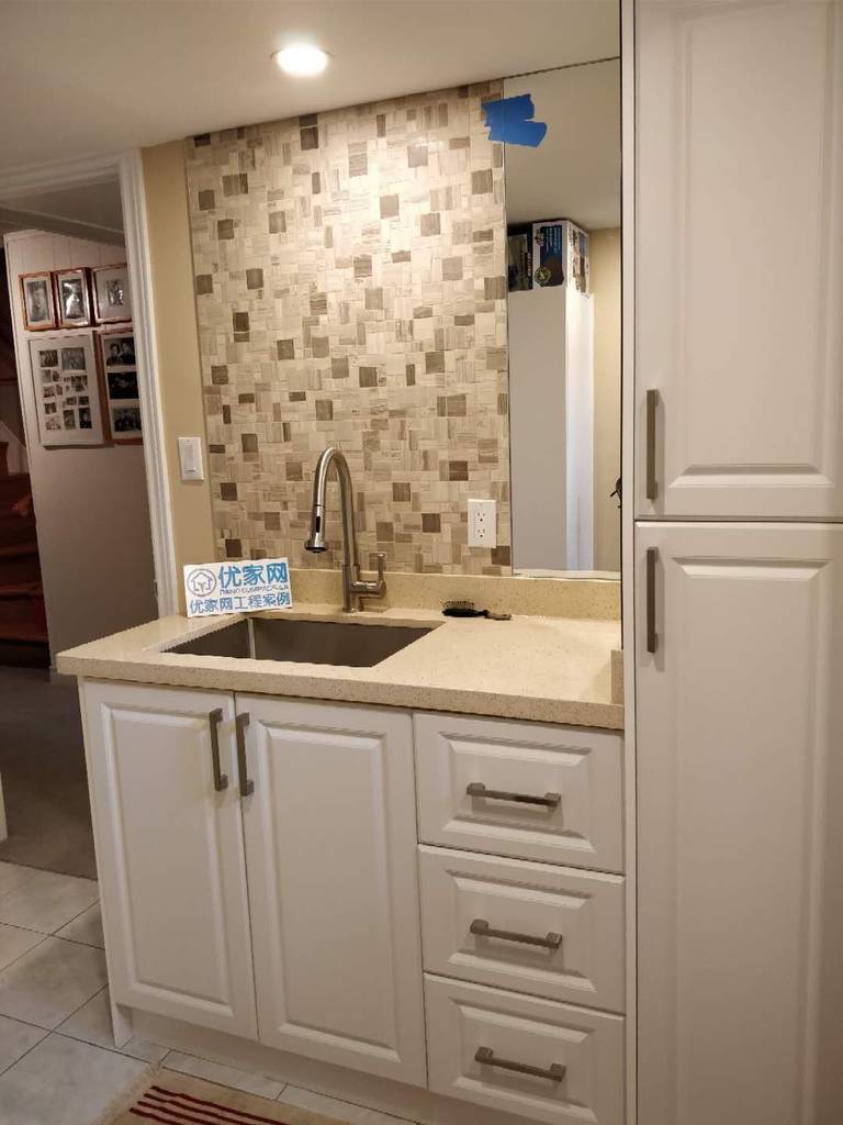 Modern basement wet bar area completed during a Scarborough interior renovation project. The space features custom white cabinetry, quartz countertop, mosaic tile backsplash, and a stainless steel sink with a modern faucet, creating a clean and functional entertainment area for the home.