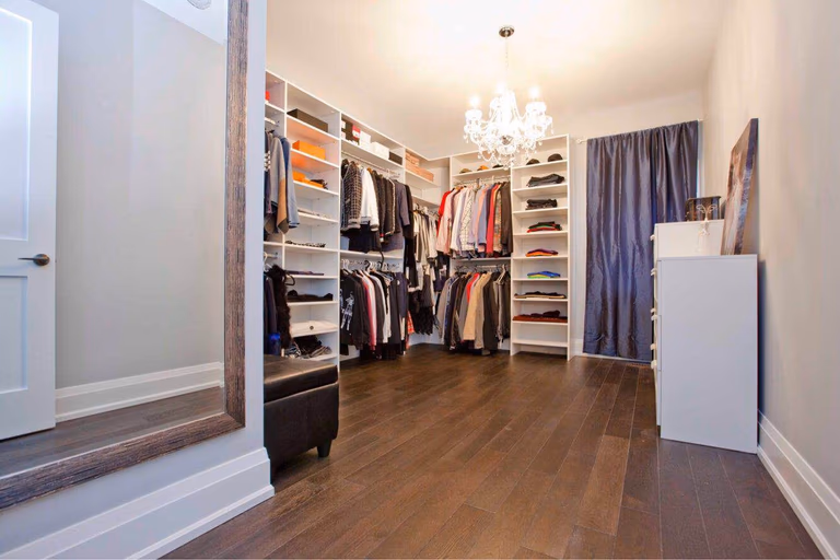 Luxury walk-in closet completed as part of a Toronto design build and whole house renovation Toronto project, featuring custom shelving systems, open wardrobe storage, hardwood flooring, and elegant lighting. This Toronto custom build home highlights functional storage planning and high-end interior finishes designed to maximize space and organization.