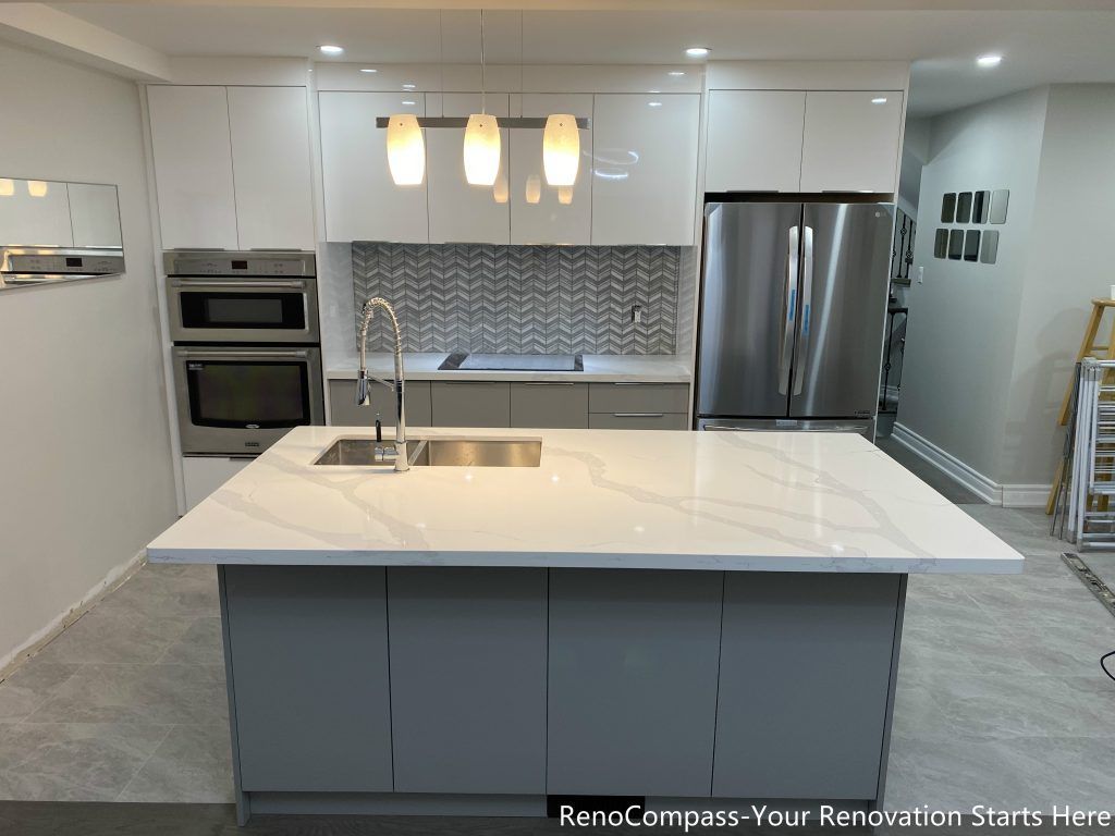 This Mississauga kitchen renovation showcases a modern open-concept design featuring a large quartz island with double sink, custom flat-panel cabinetry, and stainless steel appliances. The upgraded space includes built-in oven units, contemporary backsplash design, and pendant lighting that enhances both functionality and visual appeal. Completed by a trusted Toronto renovation company, this interior renovation focuses on maximizing storage, improving workflow, and creating a bright, elegant kitchen environment ideal for everyday living and entertaining.