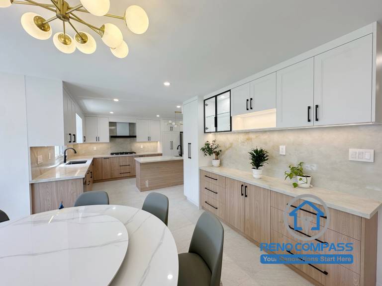 A modern open-concept kitchen and dining room featuring custom white and wood cabinetry, quartz countertops, a built-in coffee bar, and contemporary lighting. Completed as part of a luxury whole home renovation in Markham, Ontario, this elegant interior design maximizes functionality, storage, and seamless living with premium craftsmanship by Reno Compass.