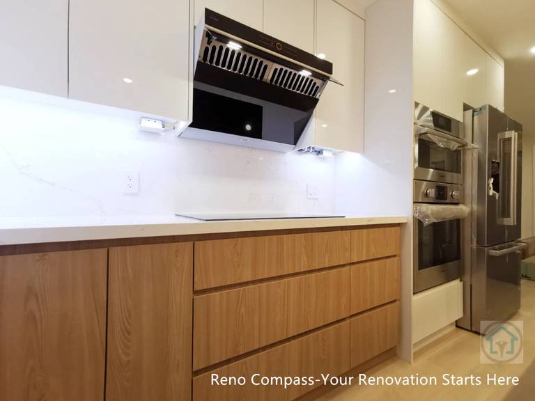 This Richmond Hill kitchen renovation features custom wood-grain base cabinetry paired with a clean white backsplash and integrated range hood system. The handle-less drawer design enhances visual continuity while improving everyday functionality and storage efficiency. Completed by Reno Compass Inc., this project reflects a modern Toronto renovation approach that balances practicality, craftsmanship, and clean architectural lines—ideal for homeowners seeking long-term livability and timeless kitchen design.