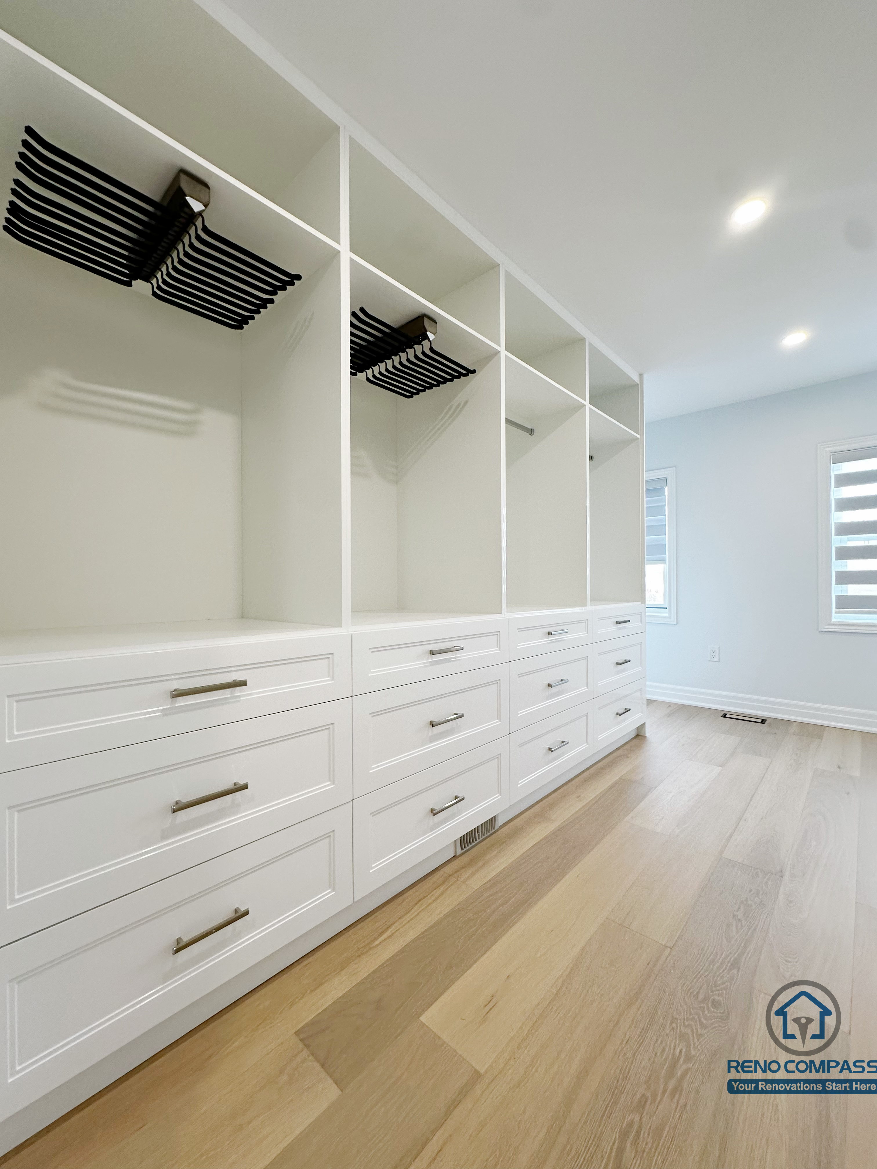 Custom walk-in closet featuring full-height white cabinetry, open shelving, integrated drawers, and dedicated hanging sections, designed to maximize storage efficiency while maintaining a clean, cohesive look.