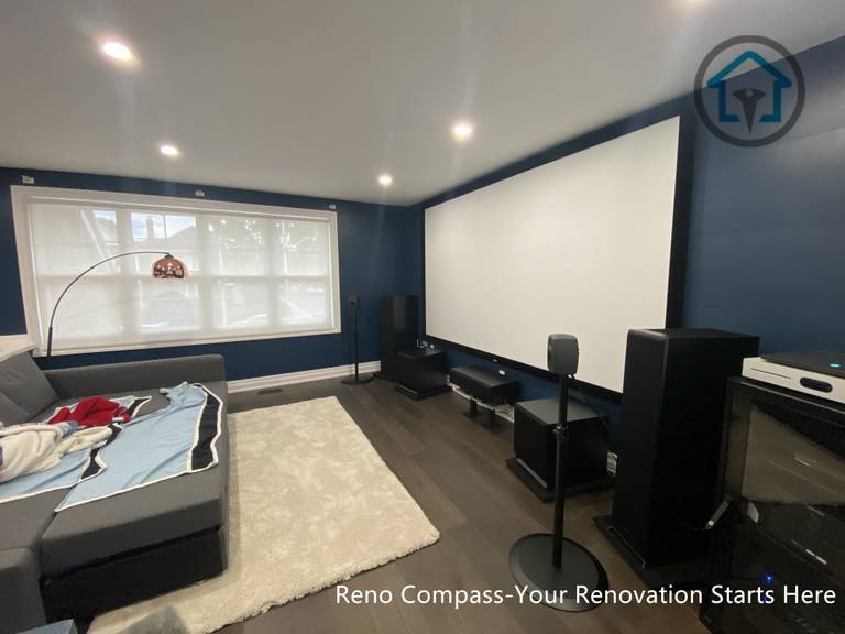 This image highlights a dedicated home theater space completed as part of a residential interior renovation in Toronto. The room is designed with a clear media-focused layout, featuring a full projection screen, integrated speaker system, and controlled lighting for an immersive viewing experience. Dark wall tones reduce glare and enhance screen contrast, while recessed ceiling lights provide balanced ambient illumination. The seating arrangement and circulation were carefully planned to maintain comfort, acoustics, and visual clarity, creating a functional yet refined entertainment environment suited for everyday family use.