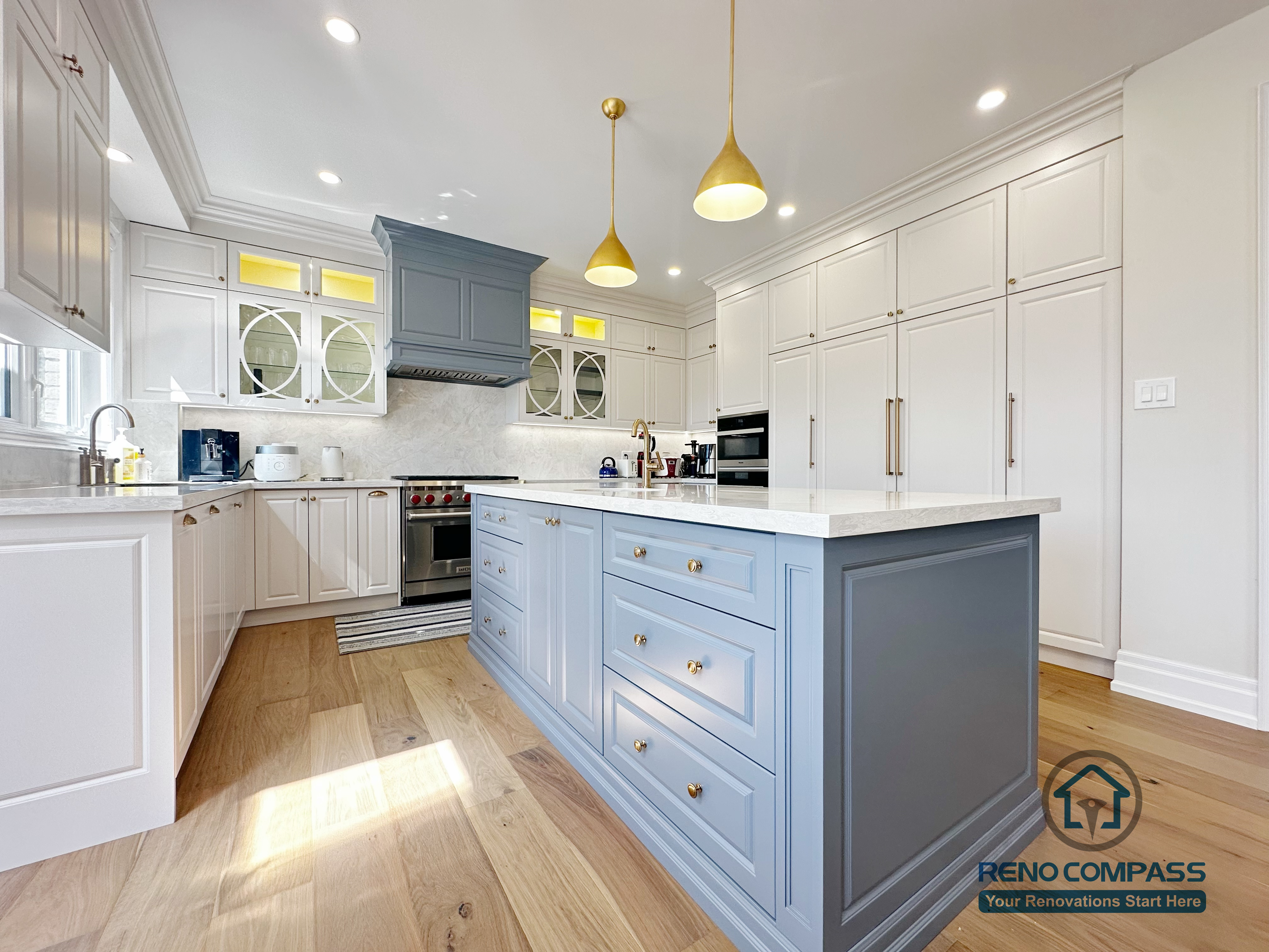 This North York kitchen renovation highlights a custom blue island with integrated drawers, full-height built-in cabinetry, and balanced recessed and pendant lighting. The layout maximizes storage efficiency while maintaining clean lines and visual symmetry, creating a refined and highly functional kitchen space designed and built by Reno Compass.
