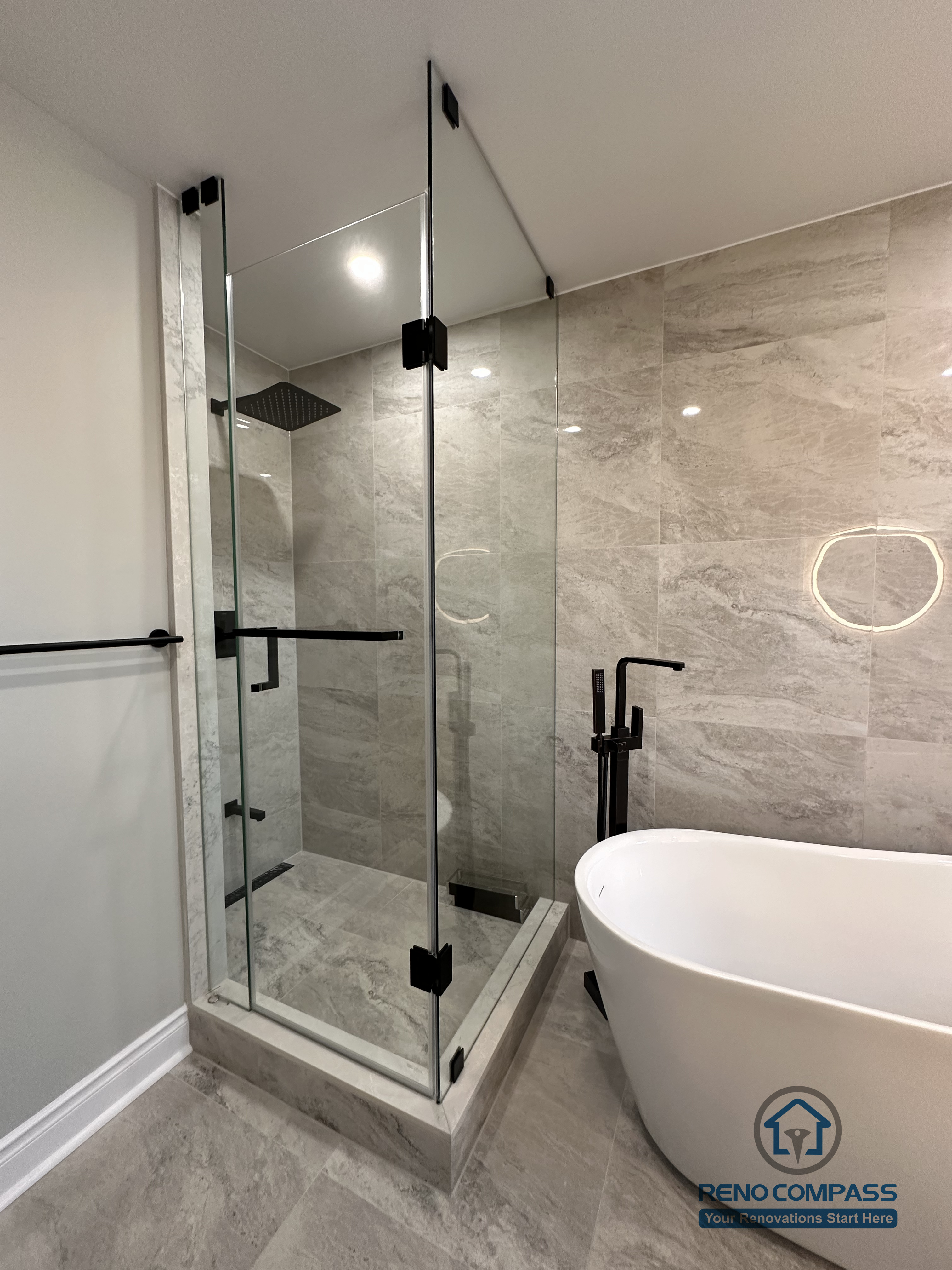 This Markham bathroom renovation features a walk-in glass shower with large-format stone-look wall and floor tiles, creating a clean and streamlined bathing area. The transparent glass enclosure maintains visual continuity along the bathroom corridor while ensuring effective water containment. Designed and built by a professional Toronto renovation company, Reno Compass Inc., the space prioritizes durability, clarity, and long-term functionality.