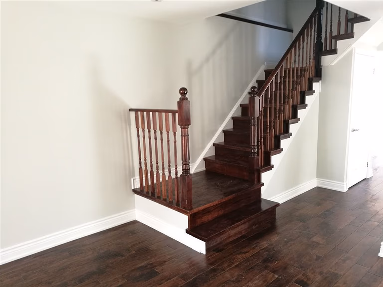 Scarborough whole-house interior renovation featuring a custom wood staircase refinishing and new hardwood flooring installation. This upgrade highlights detailed wood railing craftsmanship, modern interior finishes, and improved layout flow, creating a clean and elegant living environment by a professional Toronto renovation contractor.
