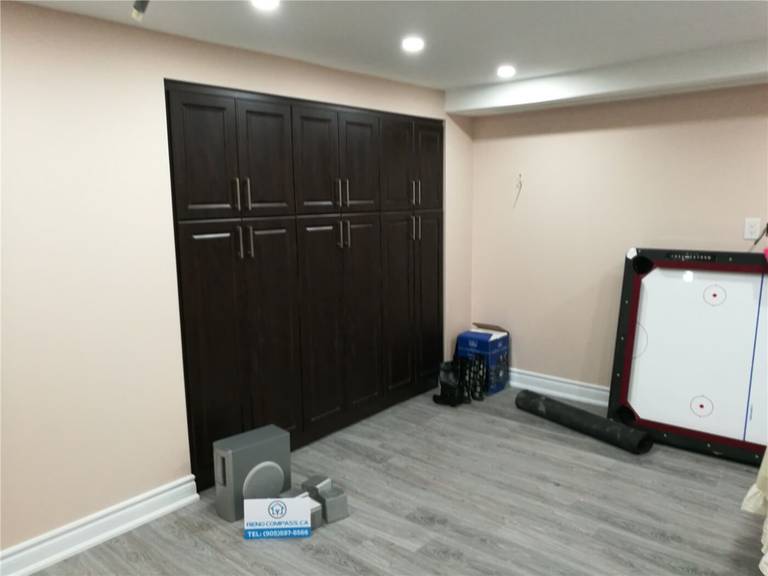 This image features custom built-in storage cabinets completed as part of a Newmarket interior renovation project. The floor-to-ceiling dark wood cabinetry provides ample storage while maintaining a clean, modern appearance. Integrated handles and recessed ceiling lighting enhance both functionality and visual balance within the space. Completed by a professional Toronto renovation company, this custom cabinetry solution improves organization, usability, and overall interior efficiency.