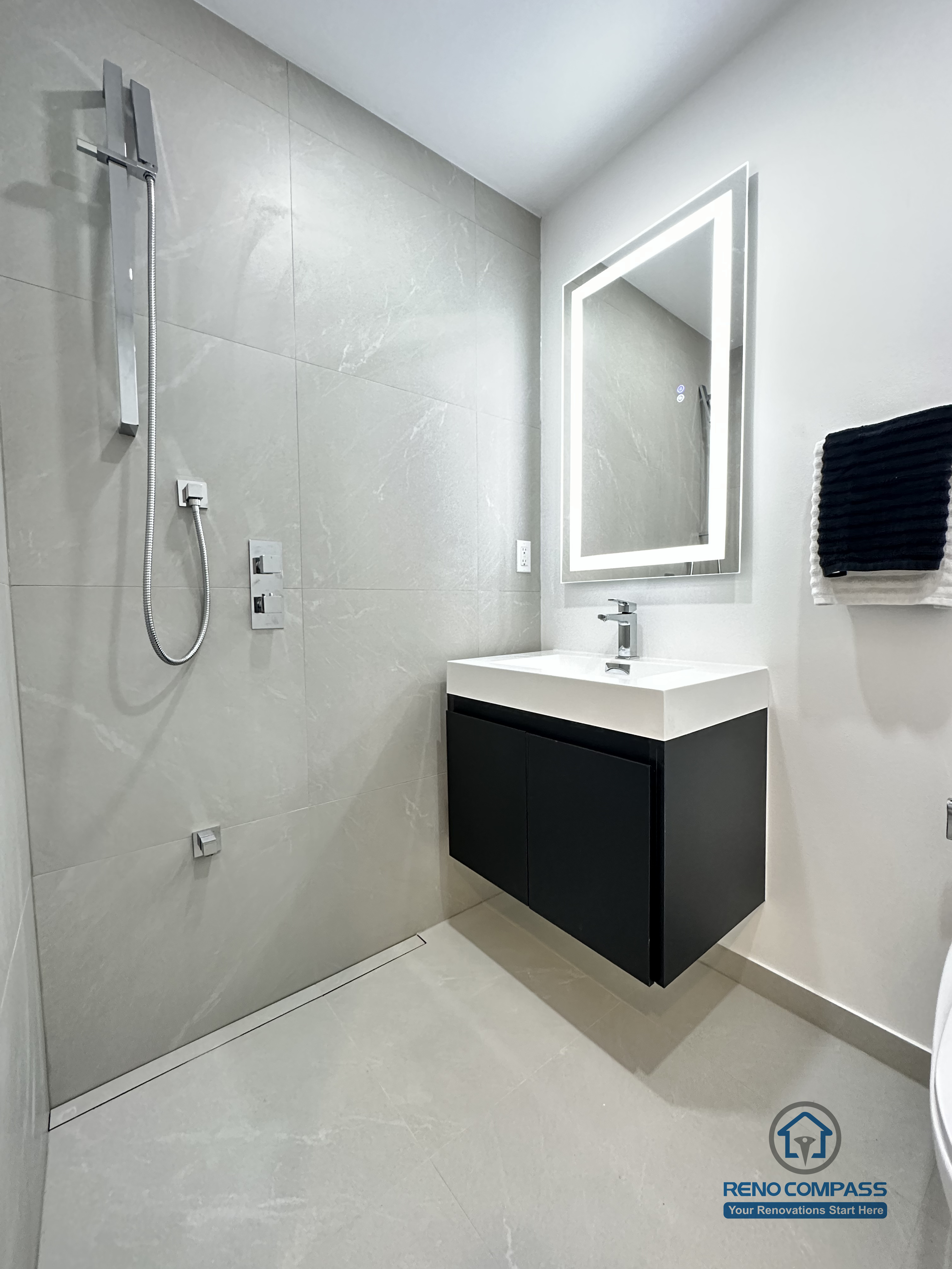 This image features a clean and modern accessible bathroom layout in Brampton, highlighting a floating vanity, integrated LED mirror, and a compact toilet designed for efficient space use. The wall-mounted vanity improves floor clearance, making the bathroom easier to clean and more accessible for daily use and pet care. Neutral-toned tiles and minimal fixtures create a calm, functional environment suitable for barrier-free living. This thoughtfully planned bathroom renovation was completed by an experienced Toronto Renovation Company specializing in accessible and pet-friendly home solutions.