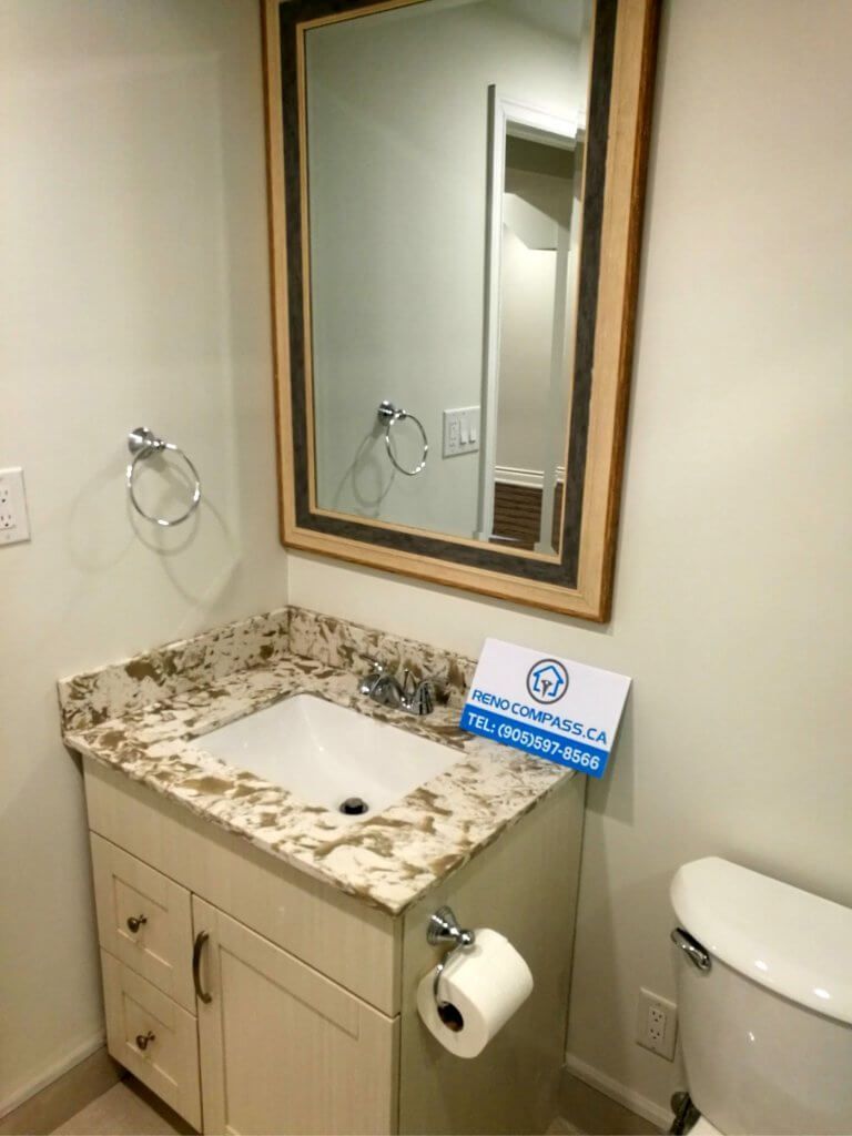 This Markham basement renovation includes a clean and functional bathroom upgrade designed for convenience and everyday use. The space features a compact vanity with a stone countertop, framed mirror, modern fixtures, and practical storage cabinetry. Neutral wall tones and efficient layout planning create a bright and comfortable basement washroom that complements the finished lower level. Completed by a professional Toronto renovation company, this basement bathroom renovation enhances both usability and property value with durable finishes and thoughtful design.