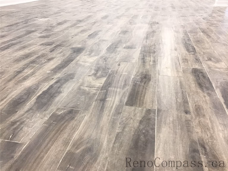 Close-up of premium wood-look vinyl plank flooring installed in a Richmond Hill basement renovation. This durable, waterproof flooring solution offers a modern grey-brown tone with natural texture, making it ideal for high-traffic basement living spaces. Professionally installed as part of a high-quality basement renovation by a trusted Toronto Renovation Company.