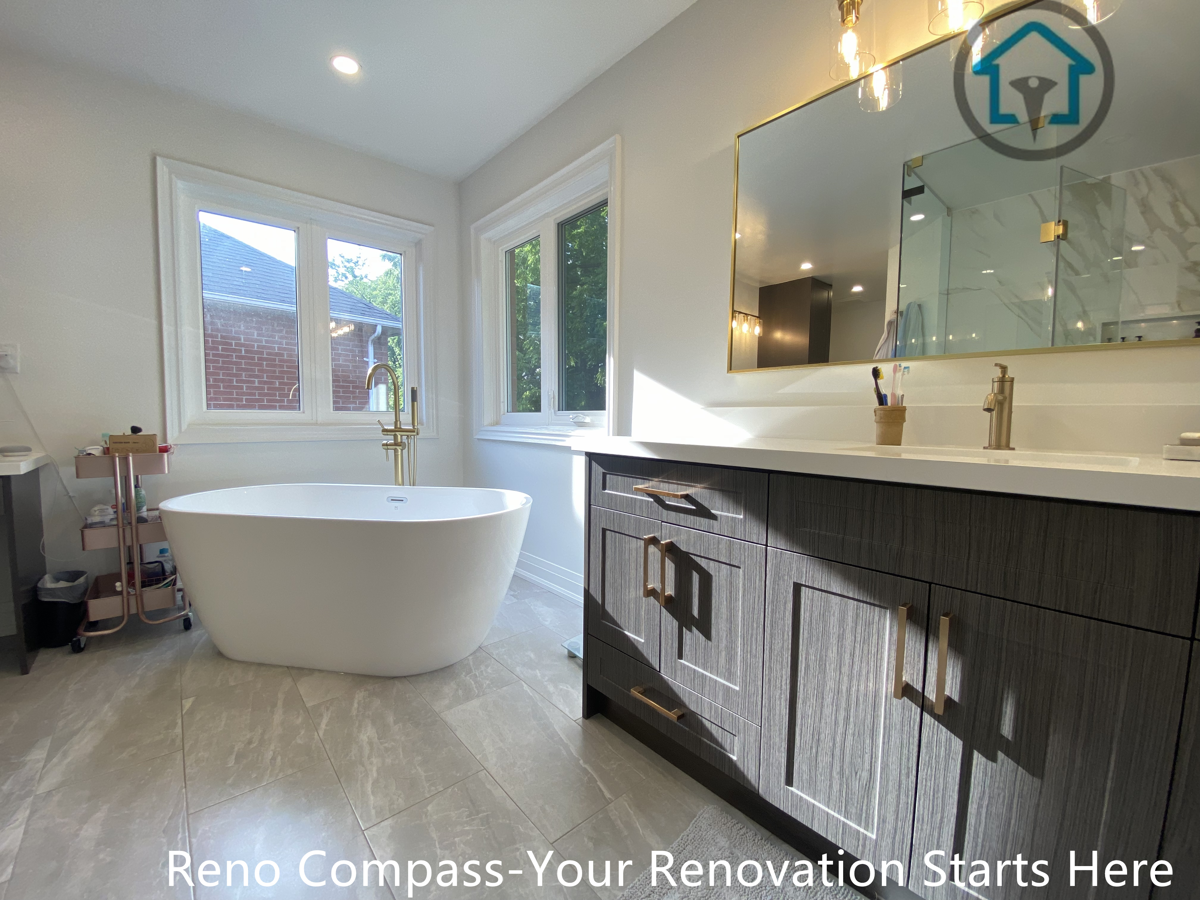 Modern Markham bathroom featuring a frameless glass walk-in shower, marble-look tiles, and a freestanding bathtub with warm brass fixtures.
