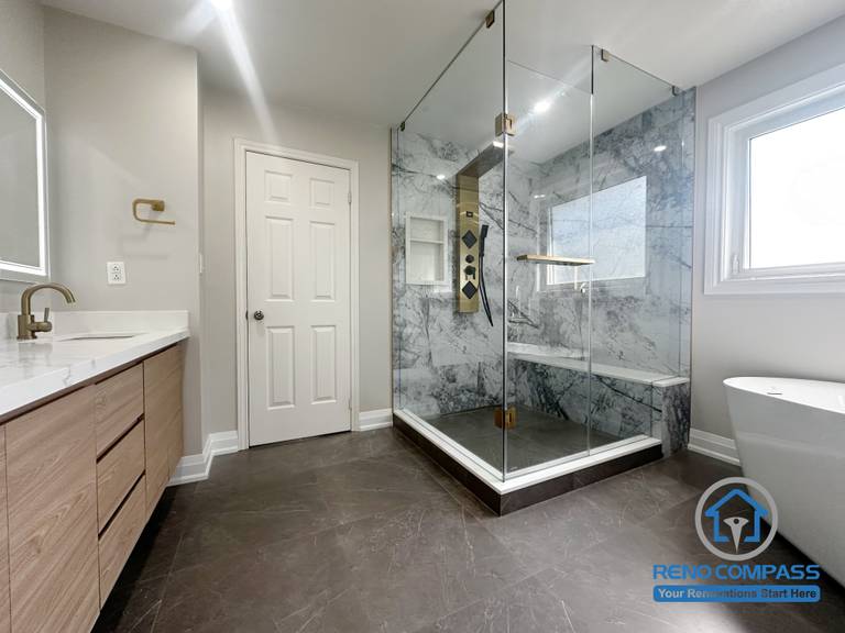 This Oakville bathroom renovation captures the overall layout, connecting the vanity area, frameless glass shower, and freestanding tub within a clear and efficient circulation plan. Consistent finishes, large-format floor tiles, and well-placed lighting help define each functional zone while maintaining visual continuity. Completed by Reno Compass, this design emphasizes everyday usability, spatial balance, and long-term performance in a modern Oakville home.
