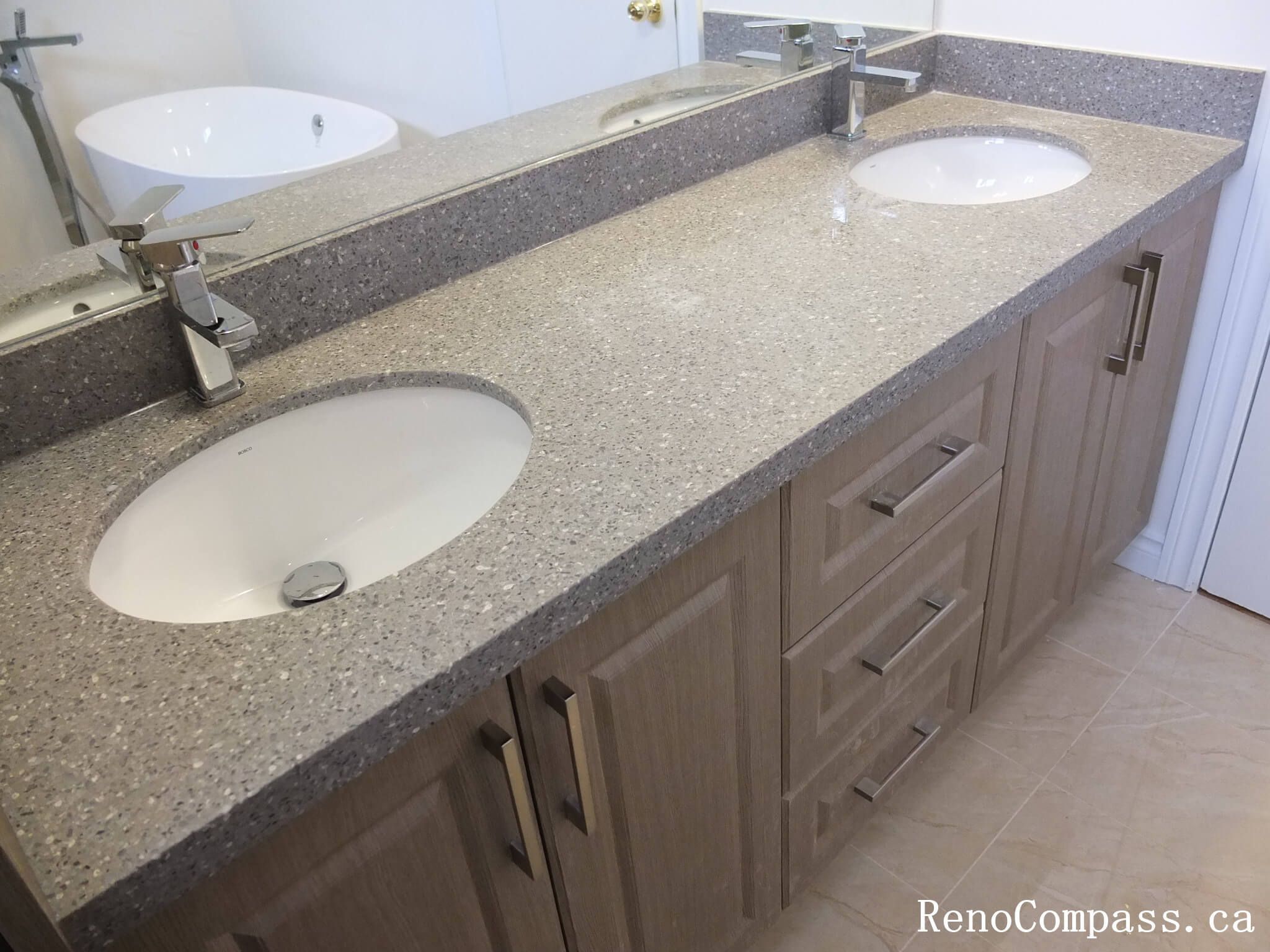 Bathroom renovation in North York highlighting a quartz countertop double sink vanity with integrated storage, modern chrome faucets, and clean-lined cabinetry. This Toronto interior renovation emphasizes durability, ease of maintenance, and practical design for shared bathroom spaces.