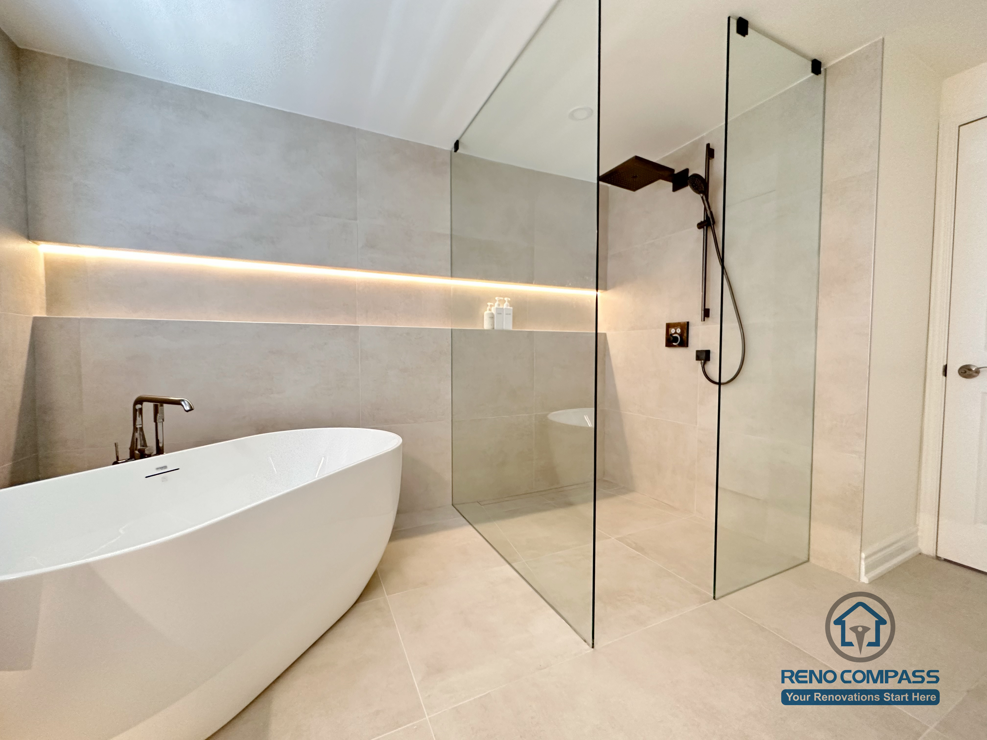 This Markham accessible bathroom renovation features a freestanding bathtub positioned within a barrier-free layout, allowing easy movement and step-free access. Large-format floor and wall tiles, integrated linear lighting, and a custom wood-tone vanity contribute to a calm, safe, and modern environment. Designed and built by a professional Toronto renovation company, Reno Compass Inc., the space prioritizes accessibility, comfort, and long-term usability.