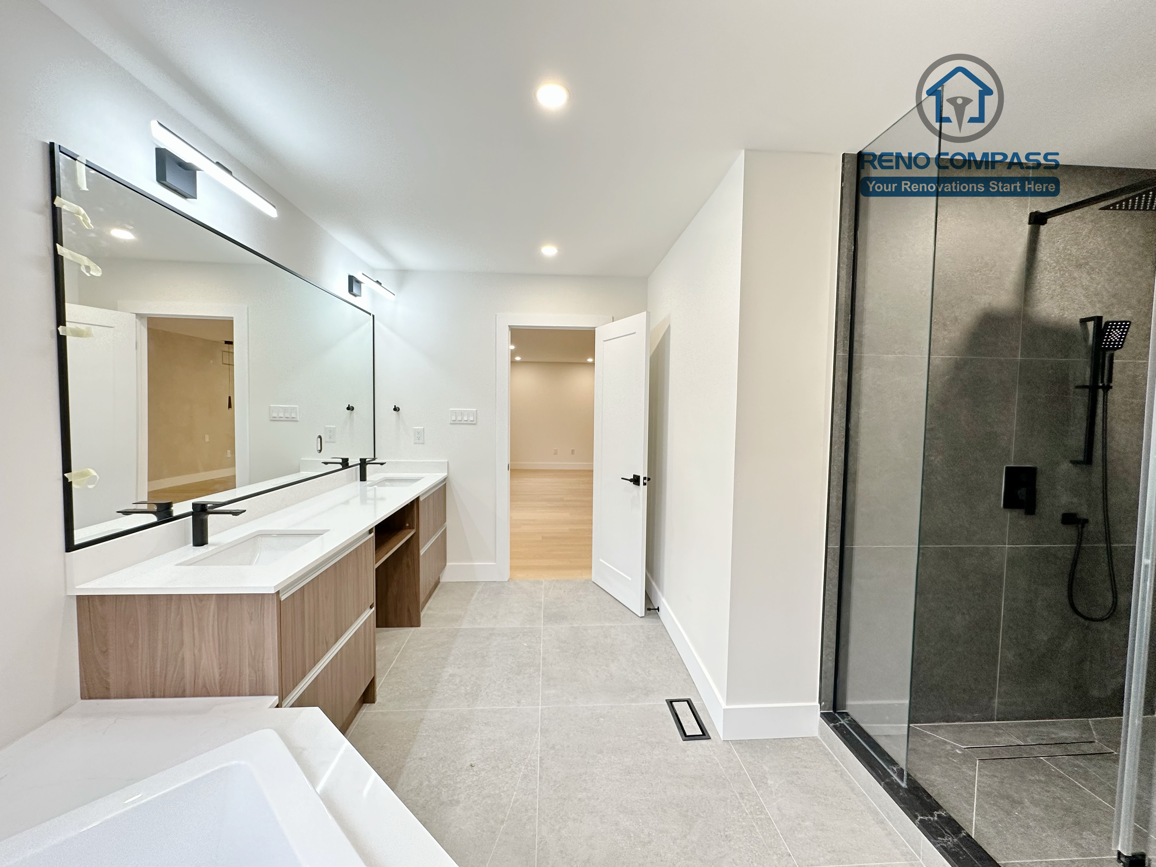 Master bathroom renovation in Richmond Hill featuring a spacious layout with a double vanity, large frameless glass shower, modern bathtub, and neutral tile flooring, creating a bright and functional contemporary bathroom.