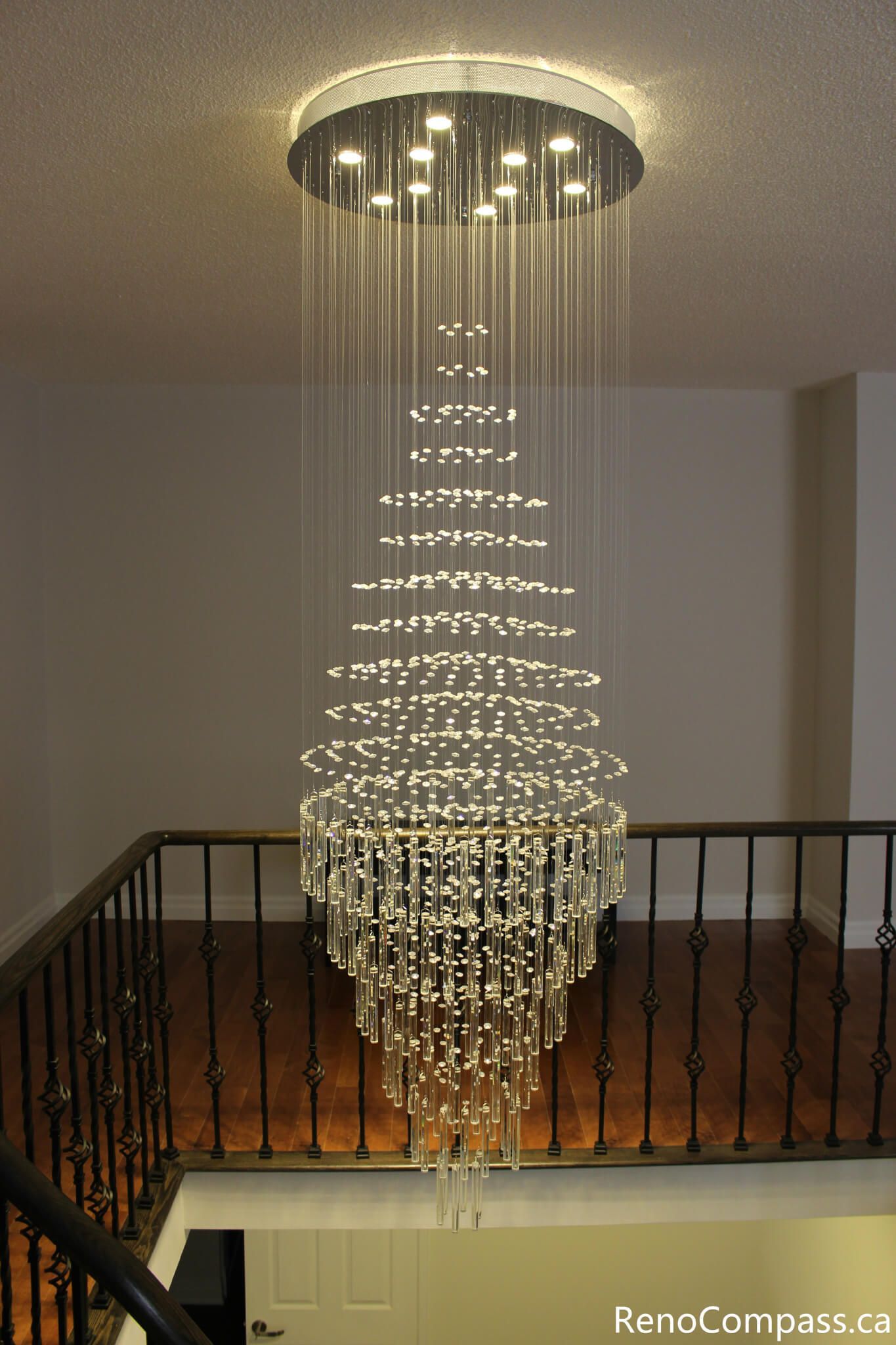 This Mississauga interior renovation features a stunning modern crystal chandelier installation above the staircase, creating a luxurious focal point and enhancing the home's lighting design. The elegant fixture adds depth, brightness, and contemporary sophistication to the open space. Completed by a professional Toronto renovation company, Reno Compass Inc., this project highlights premium interior upgrades and detailed finishing craftsmanship.