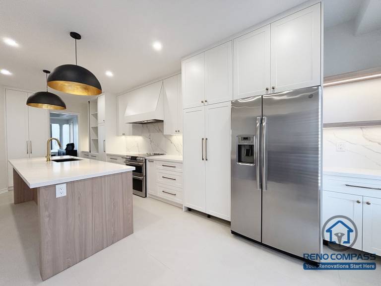 This Oakville kitchen renovation presents a clear view of the integrated appliance wall paired with a central island, emphasizing proportion, circulation, and functional balance. Full-height cabinetry conceals storage and appliances for a clean, uninterrupted appearance, while the island anchors the space for preparation and everyday interaction. Consistent finishes and restrained detailing help maintain visual order throughout the kitchen. Completed by Reno Compass, this design reflects a practical and well-structured approach to modern Oakville kitchen renovation.