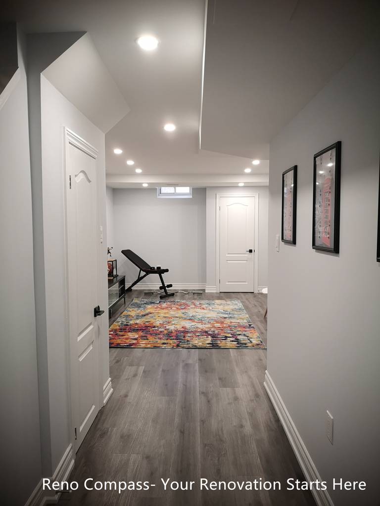 This Whitby basement renovation features a finished hallway that connects the staircase to the main basement living and recreation area. Wood-look flooring runs continuously throughout the space, enhancing visual flow and consistency. Recessed ceiling lights provide even illumination, while clean wall finishes and minimal trim details create a modern, uncluttered appearance. The hallway layout improves circulation and accessibility, making the basement suitable for multi-purpose use such as a home gym, entertainment area, or additional living space.
