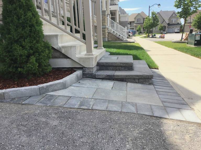 This Markham landscaping project showcases a professionally installed interlocking stone walkway and front entrance steps designed to improve both accessibility and curb appeal. The grey stone pavers create a clean transition between the sidewalk, driveway, and porch area while complementing the home’s exterior design. As a reliable Toronto Renovation Company, Reno Compass Inc. delivers precise interlocking installation and durable outdoor landscaping solutions for residential properties across the Greater Toronto Area.
