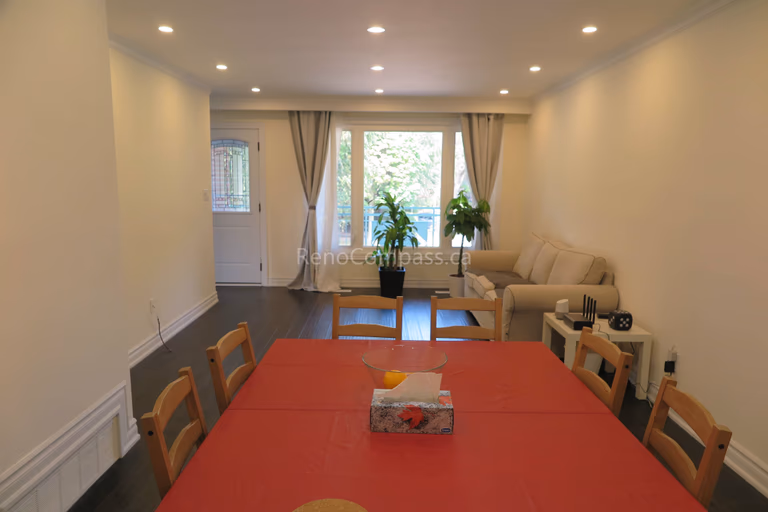 This image showcases a completed North York flooring renovation featuring an open living and dining area with dark hardwood flooring. The refreshed layout, recessed ceiling lights, and natural light from the rear windows create a bright and welcoming interior. The seamless flooring installation enhances flow between spaces, improving both functionality and visual balance. As a professional Toronto Renovation Company, Reno Compass Inc. delivers high-quality flooring solutions that elevate everyday living while maintaining clean design and long-term durability.