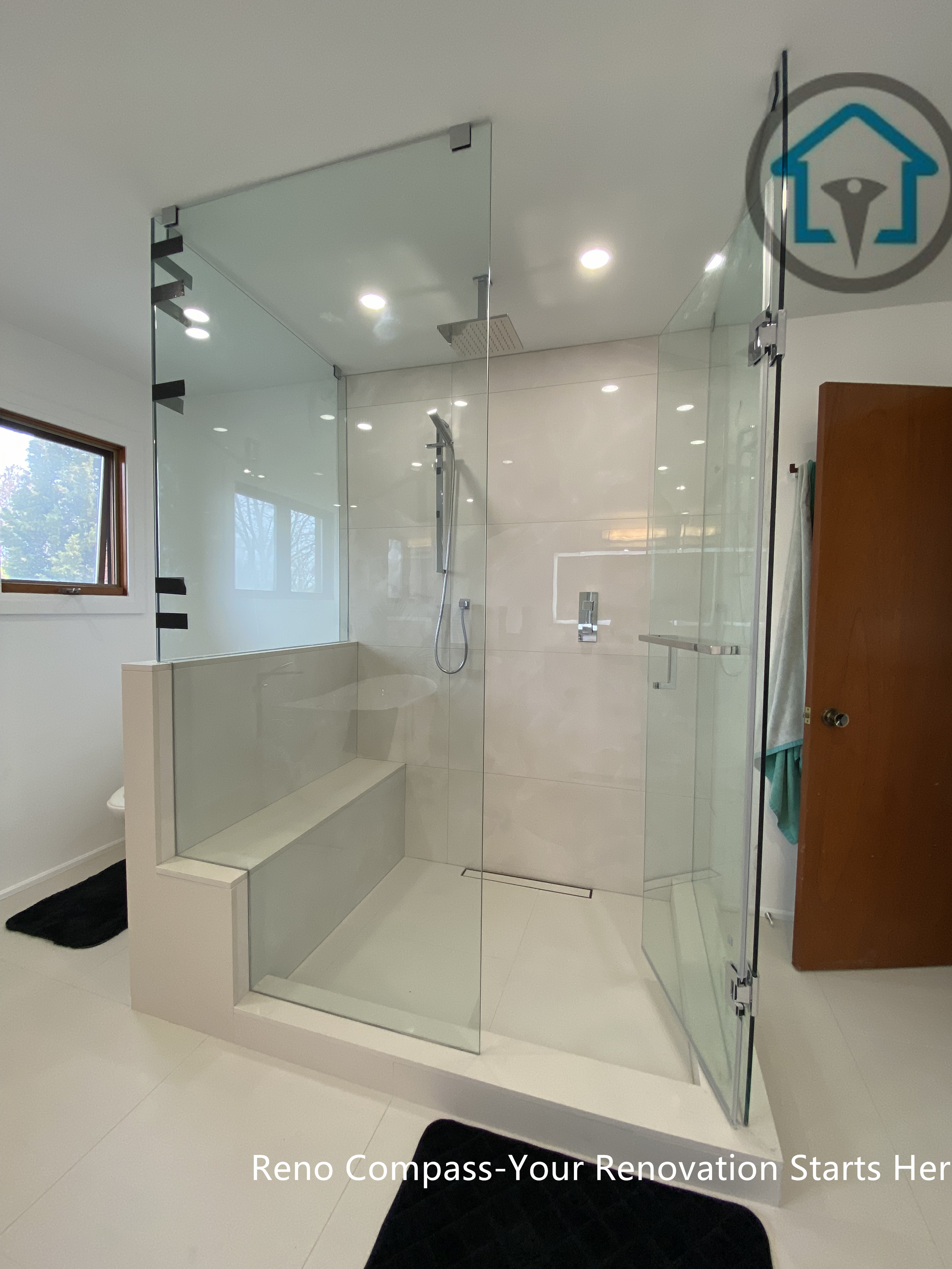 Spacious bathroom renovation in Brampton featuring a full-height frameless glass walk-in shower with a built-in bench and curbless entry. Large-format wall tiles, recessed lighting, and a linear drain create a bright, open, and modern shower space. Completed by a trusted Toronto renovation company, this design improves accessibility, safety, and everyday comfort while maintaining a clean, contemporary aesthetic.