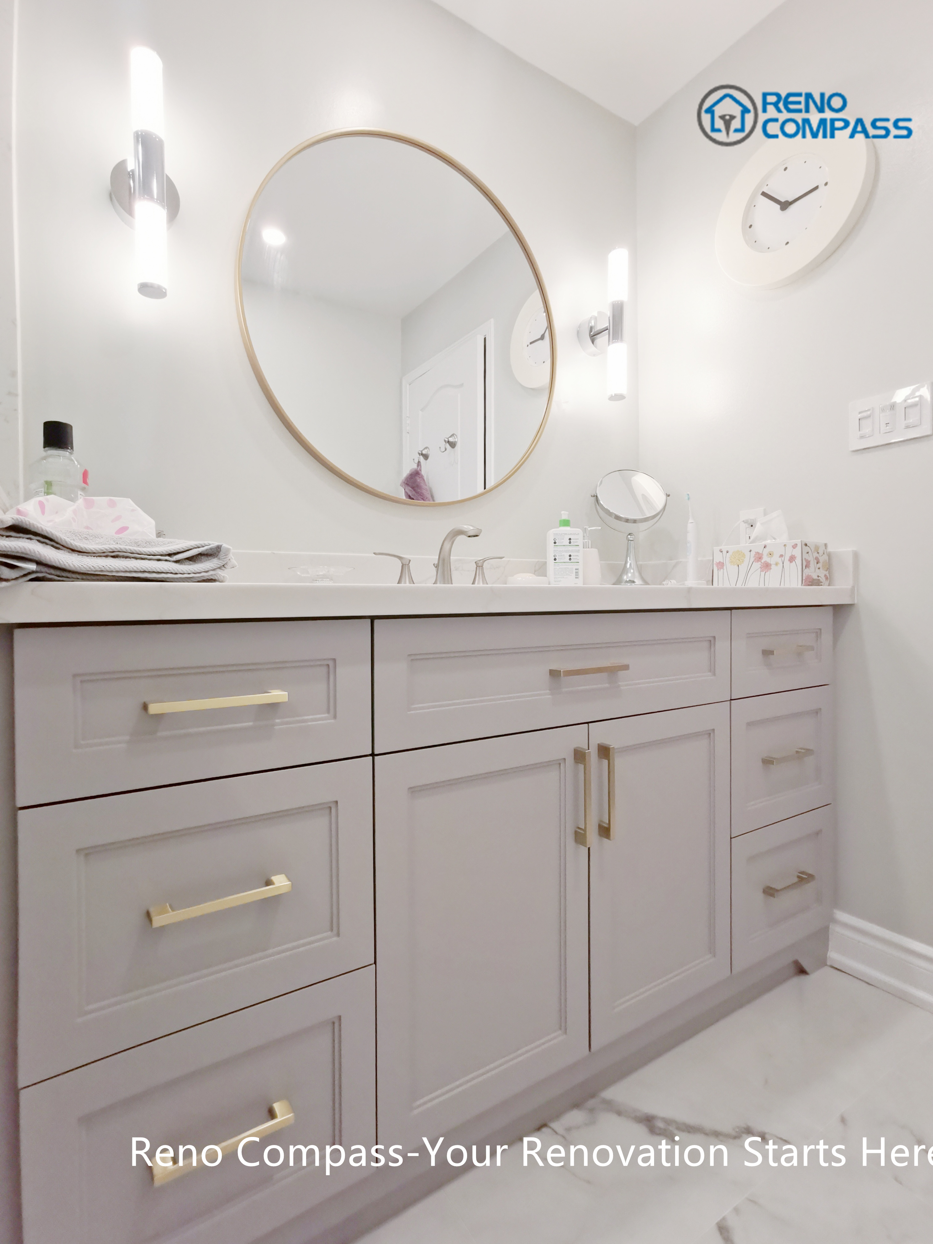 This Mississauga bathroom renovation features a custom vanity with soft grey cabinetry, brushed gold hardware, and a clean quartz countertop. A round framed mirror paired with vertical wall sconces provides balanced lighting for daily use while enhancing the overall elegance of the space. Thoughtful storage design and refined finishes reflect the attention to detail and craftsmanship expected from a professional Toronto renovation company.
