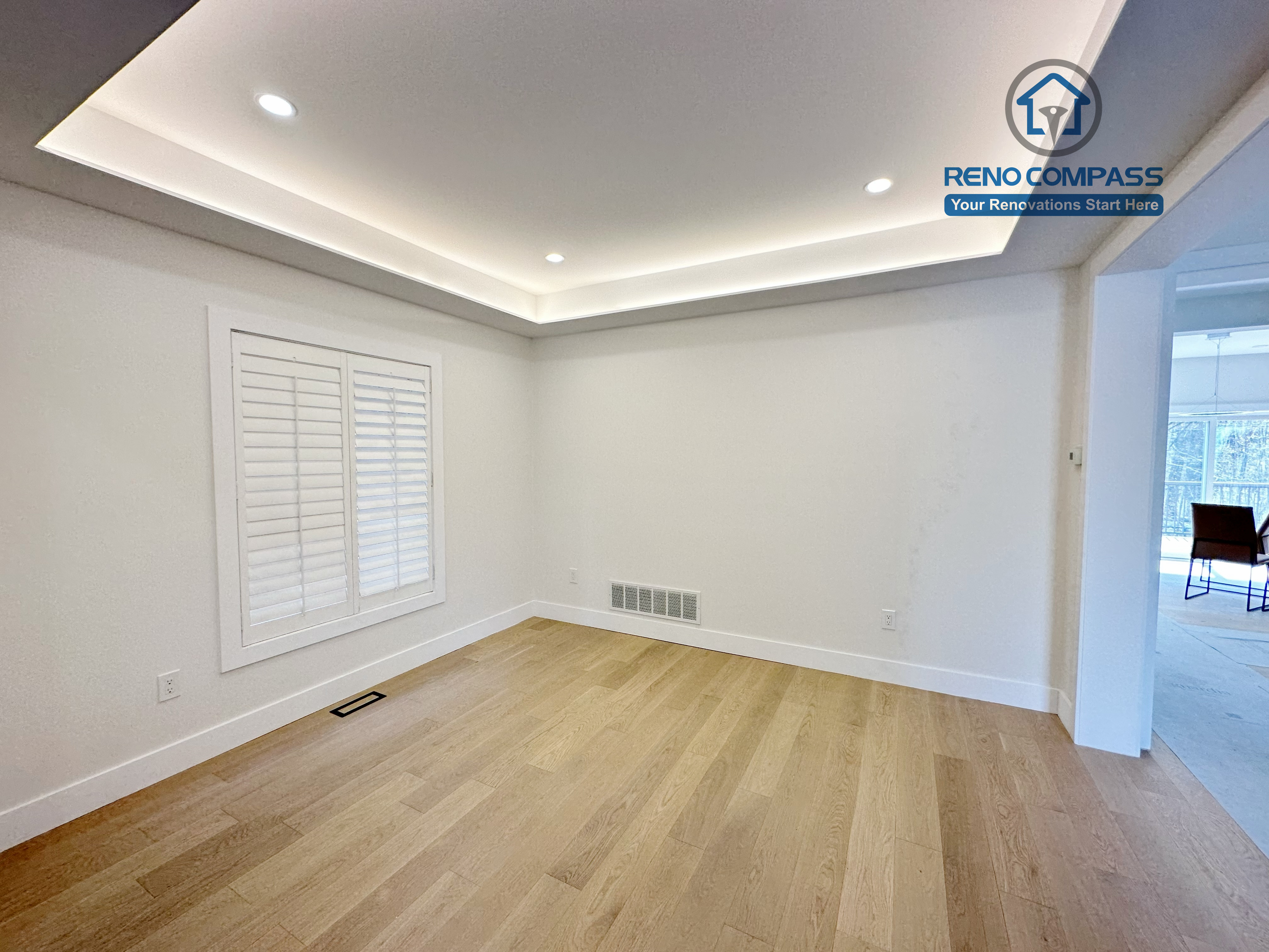 Spacious living area in a Richmond Hill home featuring light-tone hardwood flooring, a modern tray ceiling with recessed lighting, and large windows that enhance brightness and a clean, contemporary interior.