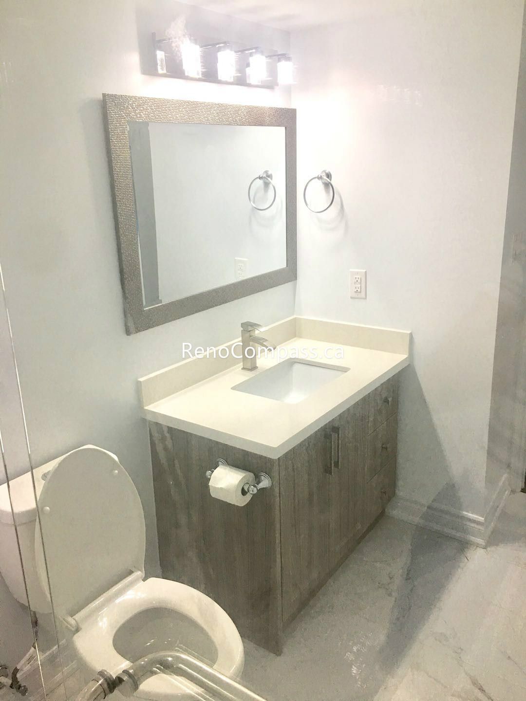 This Toronto basement renovation highlights a newly upgraded bathroom vanity with a modern sink, quartz countertop, and stylish mirror lighting. The wood-tone cabinet, updated fixtures, and clean tile flooring create a bright and functional bathroom space. Completed by Reno Compass Inc., this basement bathroom upgrade enhances both daily comfort and home value for Toronto homeowners.