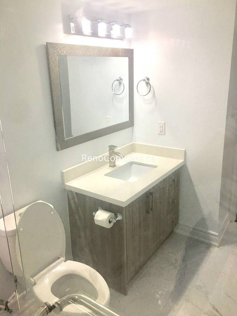 This Toronto basement renovation highlights a newly upgraded bathroom vanity with a modern sink, quartz countertop, and stylish mirror lighting. The wood-tone cabinet, updated fixtures, and clean tile flooring create a bright and functional bathroom space. Completed by Reno Compass Inc., this basement bathroom upgrade enhances both daily comfort and home value for Toronto homeowners.