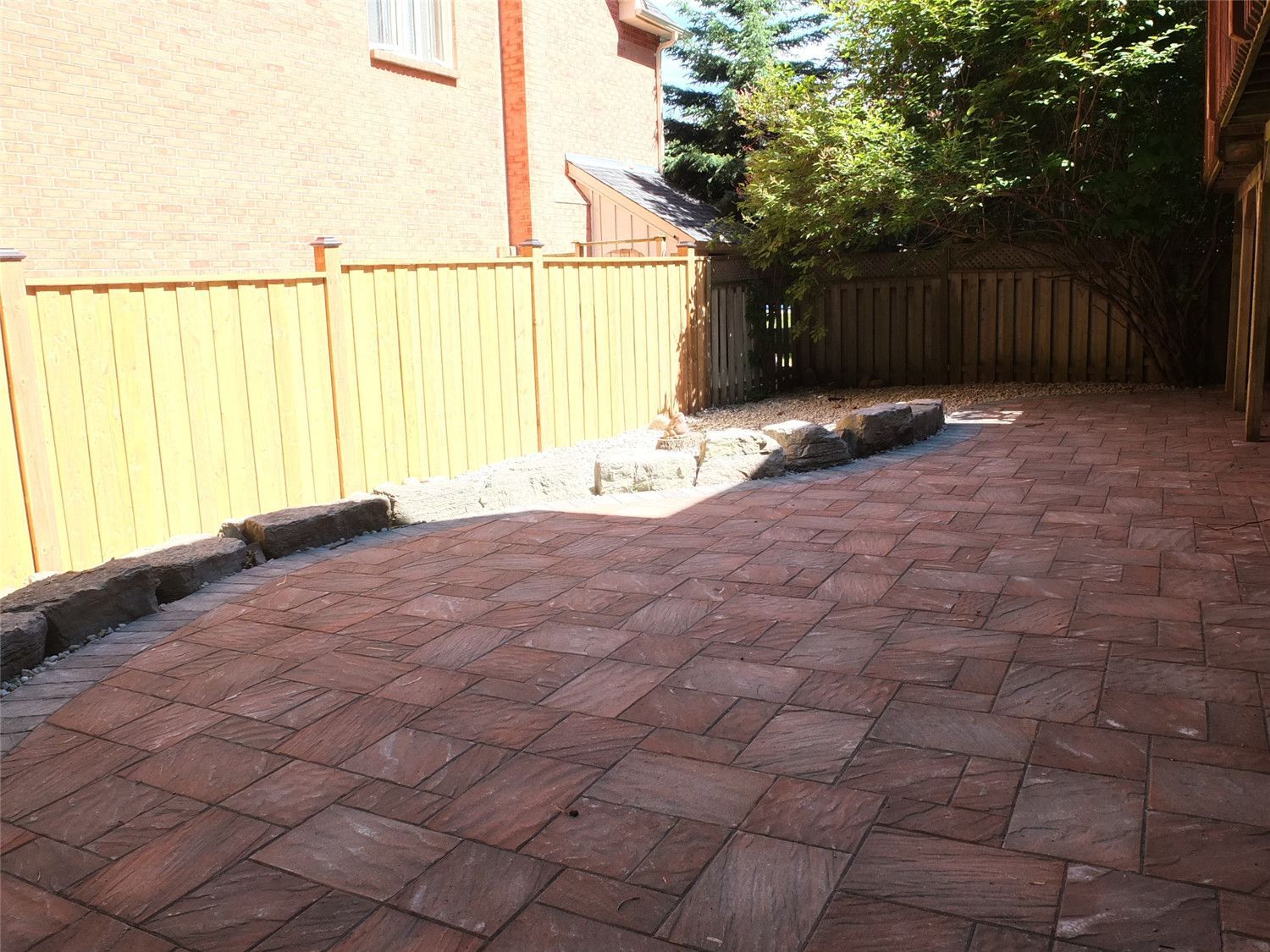 This Aurora landscaping renovation highlights a curved interlocking patio seamlessly integrated with a decorative gravel relaxation area. The contrasting stone border defines the transition between the paver surface and the natural stone feature zone, creating visual depth and balance.

Reno Compass Inc. carefully designed the layout to preserve mature trees while enhancing usability. The addition of river stone, large accent rocks, and a hammock-ready space transforms the backyard into a tranquil retreat that blends structure with nature.