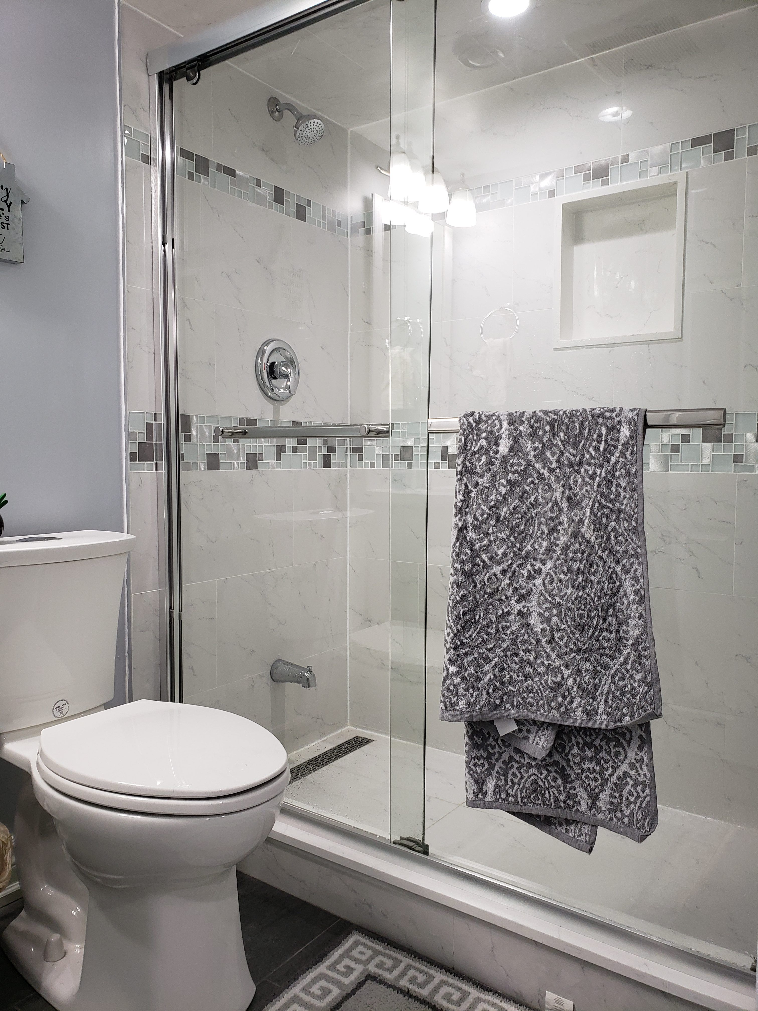 This basement bathroom renovation in Newmarket, Toronto features a clean and modern design with a glass-enclosed shower, full-height wall tiles, and upgraded plumbing fixtures. The shower area includes a built-in niche and decorative accent tile band, combining functionality with contemporary style. Neutral tones and bright lighting enhance the sense of space, making the bathroom feel fresh and inviting despite the basement setting. Durable floor tiles and moisture-resistant materials ensure long-term performance and easy maintenance. Completed by a professional Toronto renovation company, this basement bathroom upgrade focuses on practicality, comfort, and modern interior aesthetics.