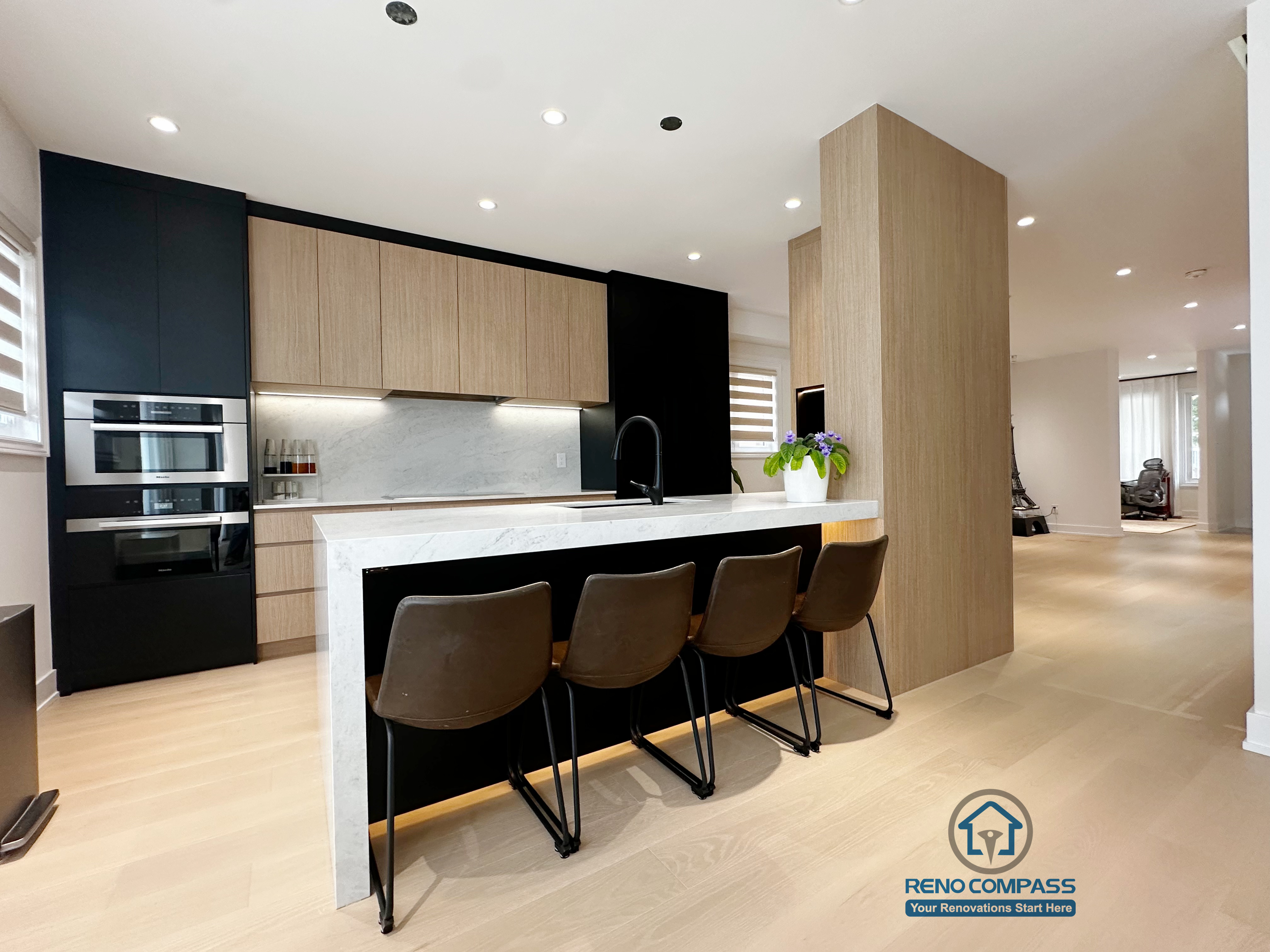 A modern Markham kitchen renovation showcasing a waterfall-edge kitchen island, seamless built-in appliances, and custom cabinetry. This project by Reno Compass creates a bright, functional space ideal for cooking and entertaining.