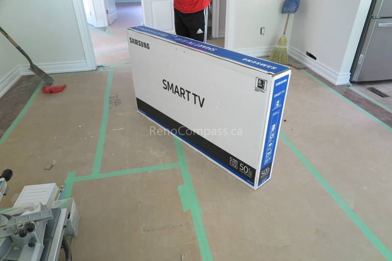Television delivery and installation preparation during a North York interior renovation project. The image shows floor protection, taped pathways, and careful staging before TV mounting, completed by a professional Toronto renovation company focused on protecting finished surfaces and maintaining a clean renovation process.